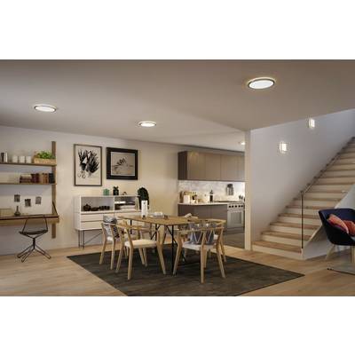 Moderne, offene Küchen- und Essbereich mit Holzmöbeln, Treppe rechts, Wanddekorationen links und gemütlicher Beleuchtung.