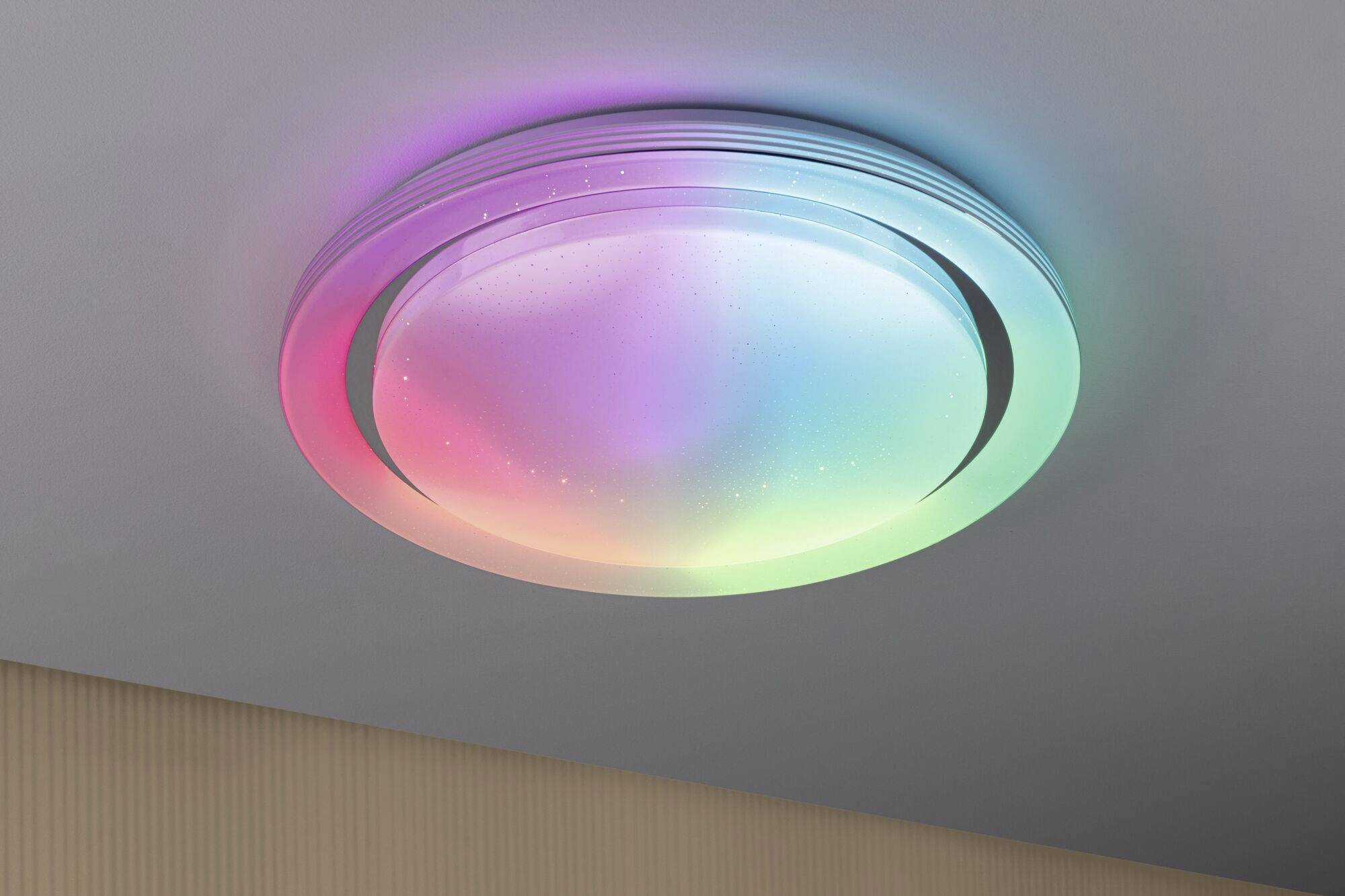 Deckenleuchte mit Regenbogenfarben, die von einem hellen Zentrum nach außen strahlen, sorgt für stimmungsvolle Beleuchtung.