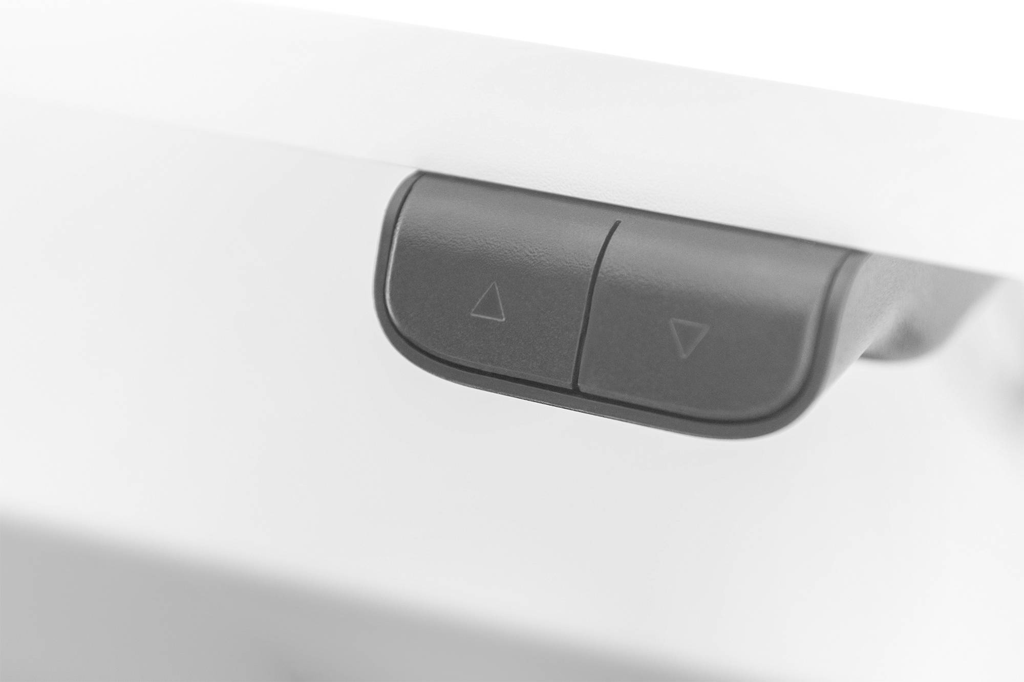 Zwei schwarze Knöpfe an der Kante eines Tisches, jeweils mit einem nach oben und einem nach unten zeigenden Pfeil markiert.