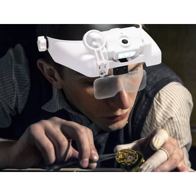 Person trägt eine Vergrößerungsbrille mit LED-Licht und arbeitet konzentriert an einem kleinen Uhrwerk mit Werkzeug in der Hand.