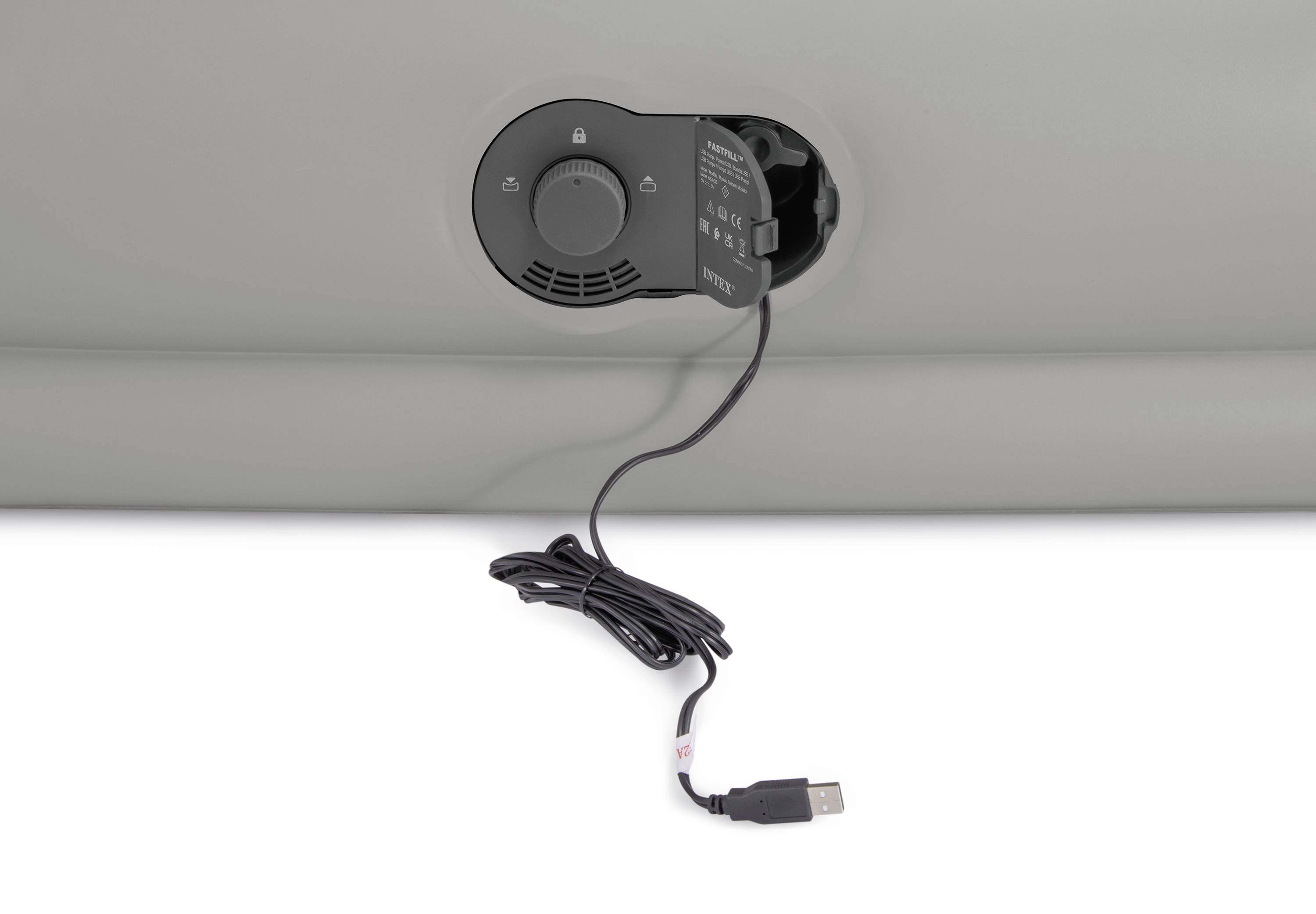 Ein USB-Kabel ist an einen grauen Kunststoffanschluss mit einer Klappe angeschlossen. Die Klappe zeigt Symbole und Text.