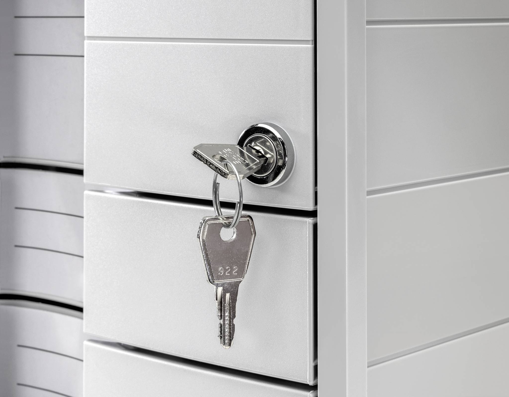 Schubladenschrank mit einem Schlüssel im Schloss, teilweise geöffnet. Darin sind mehrere abgeschlossene Fächer erkennbar. 