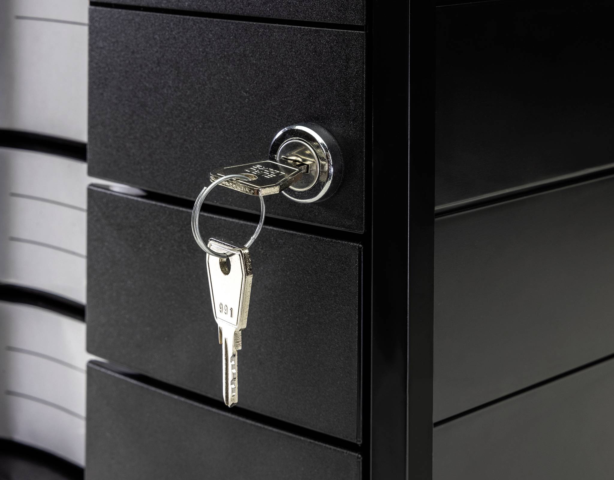 Schwarz lackierter Aktenschrank mit eingestecktem Schlüssel im Schloss. Der Schrank steht leicht geöffnet, was auf Zugriff hinweist.