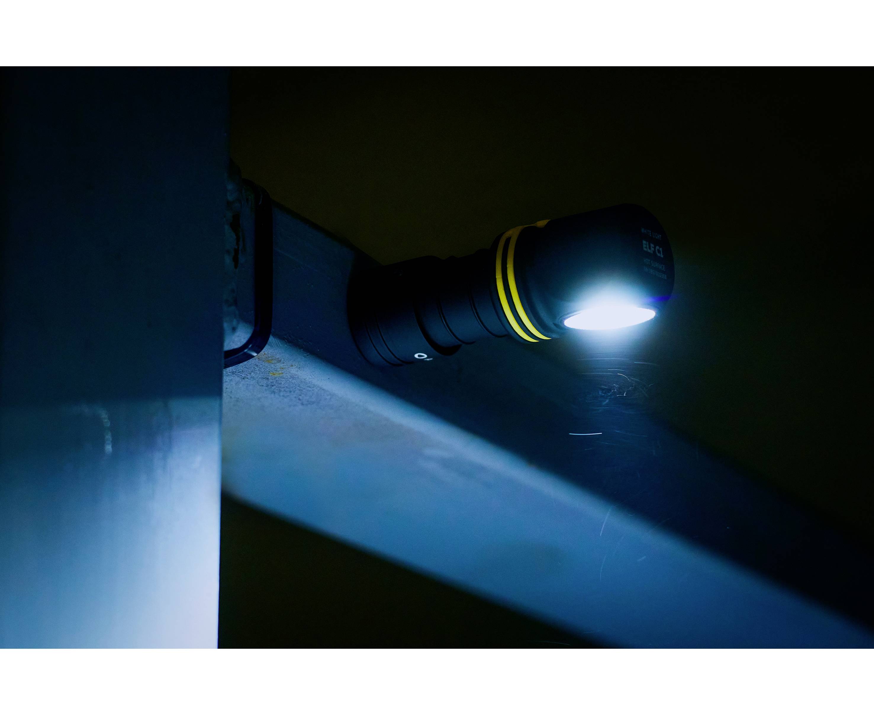 Eine Taschenlampe strahlt blaues Licht aus, montiert an einer dunklen Metalloberfläche.