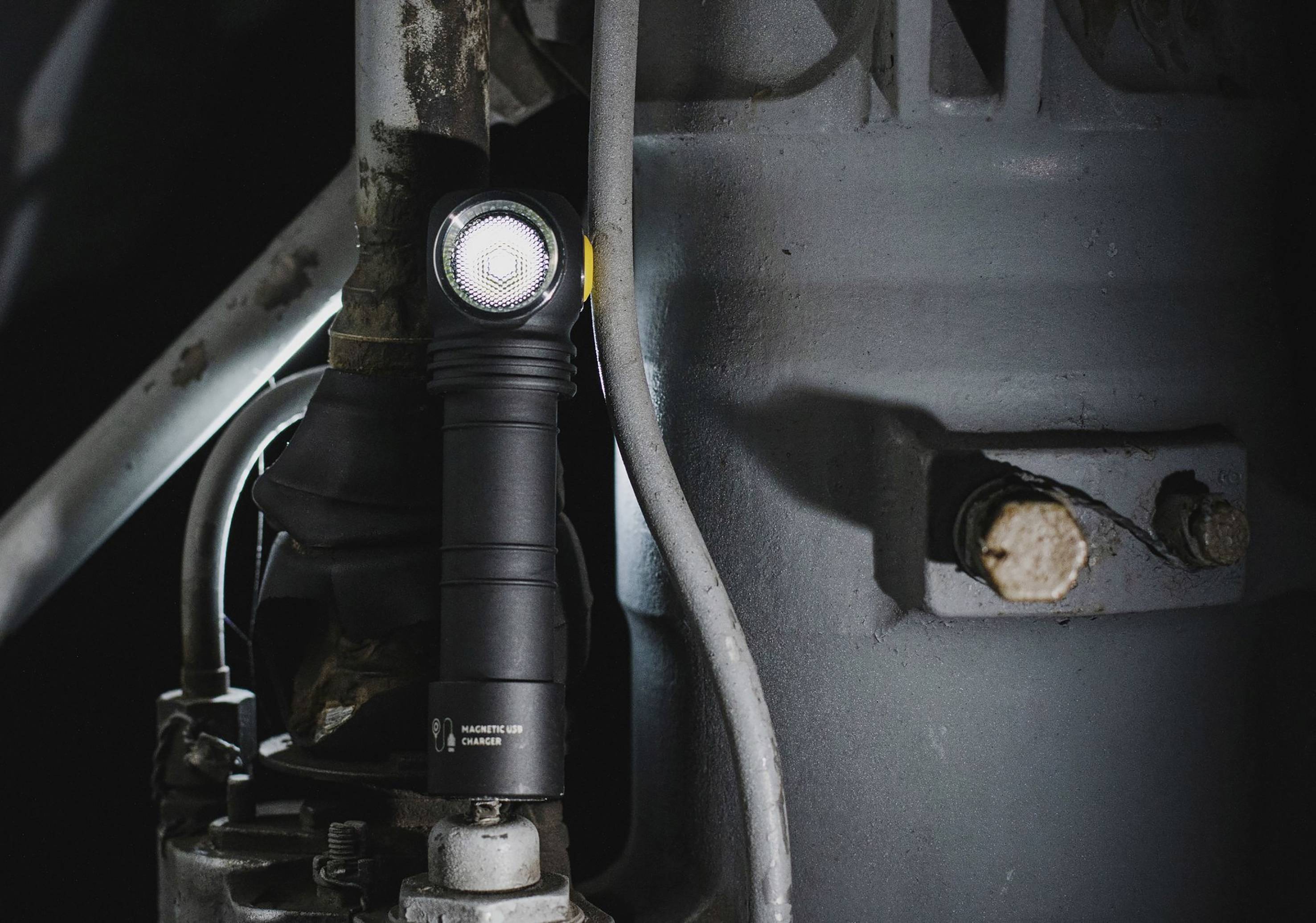 Taschenlampe magnetisch an einer Metalloberfläche befestigt, beleuchtet einen Maschinenbereich. Ideal für Arbeiten in dunklen Umgebungen.