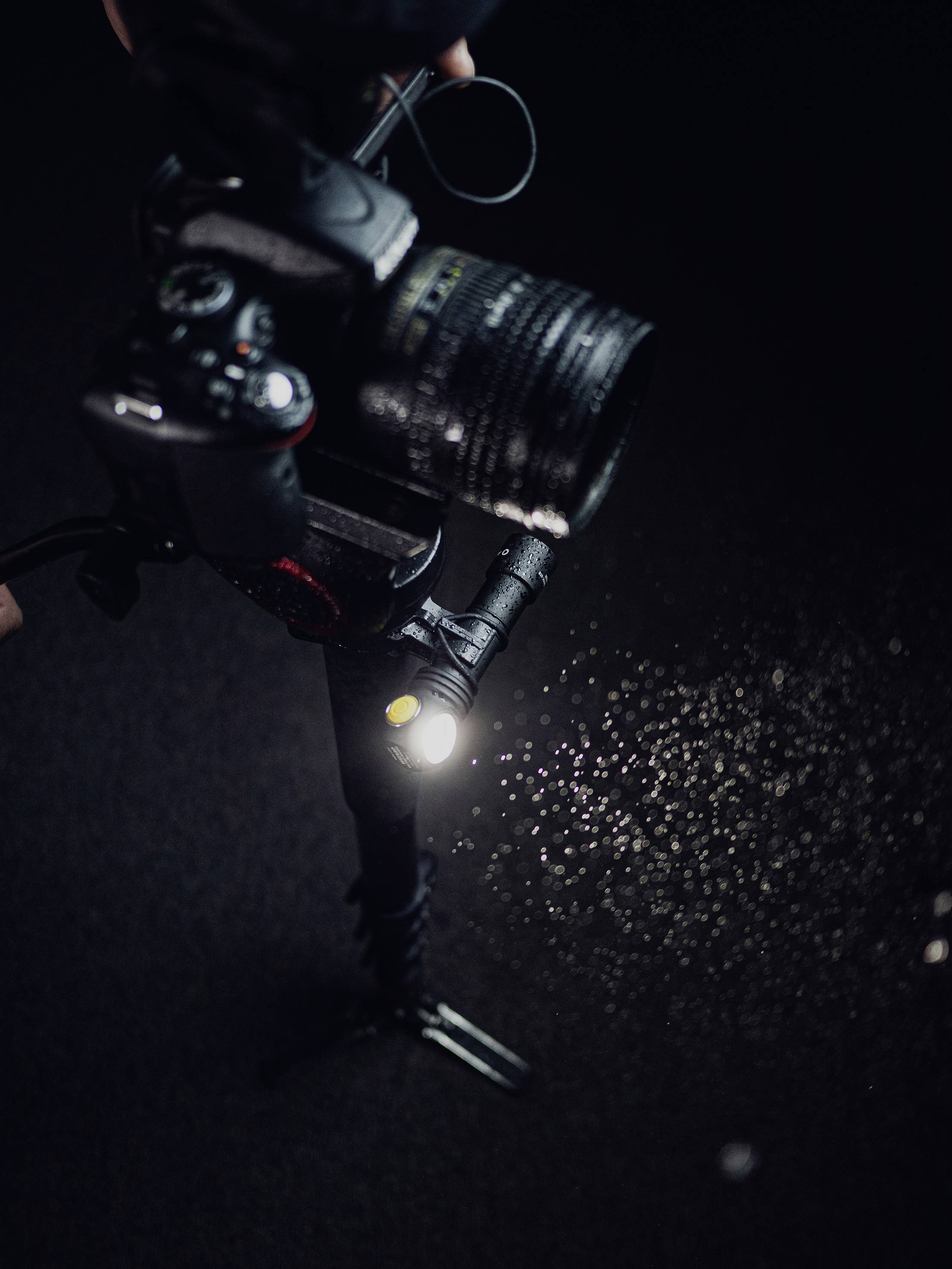 Eine Kamera fotografiert in dunkler Umgebung mit Blitzlicht. Staubpartikel sind sichtbar, beleuchtet vom Blitz.