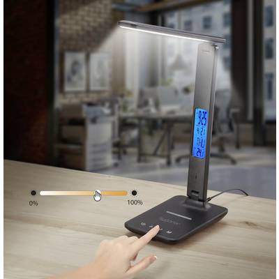 Eine Schreibtischlampe mit blauem Display zeigt Temperatur, Datum und Uhrzeit an. Der Dimmerregler wird mit einem Finger bedient.