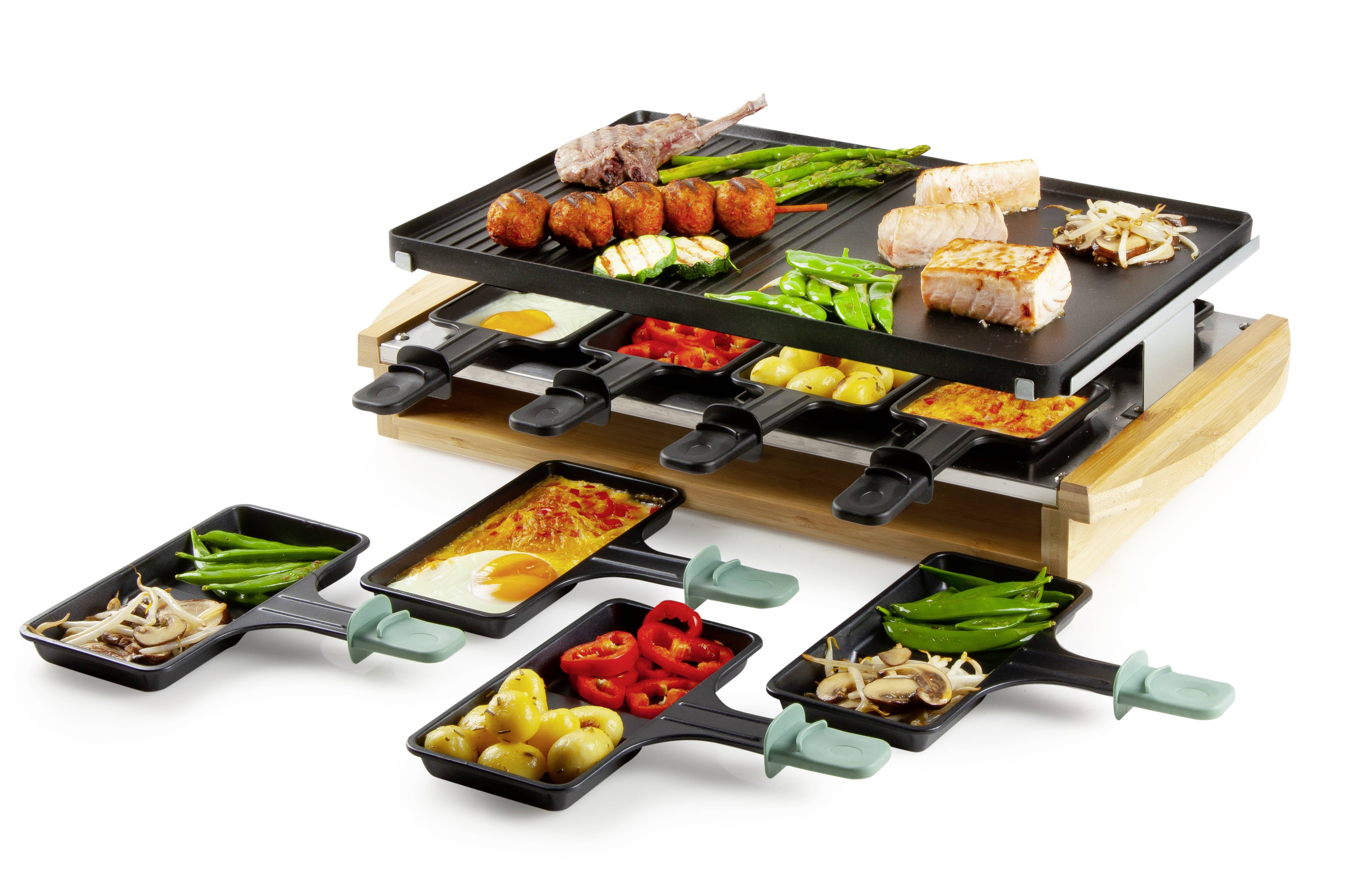 Ein Raclette-Grill mit verschiedenen Zutaten auf der oberen Platte, wie Fleisch und Gemüse. Darunter Pfännchen mit geschmolzenem Käse und Beilagen.