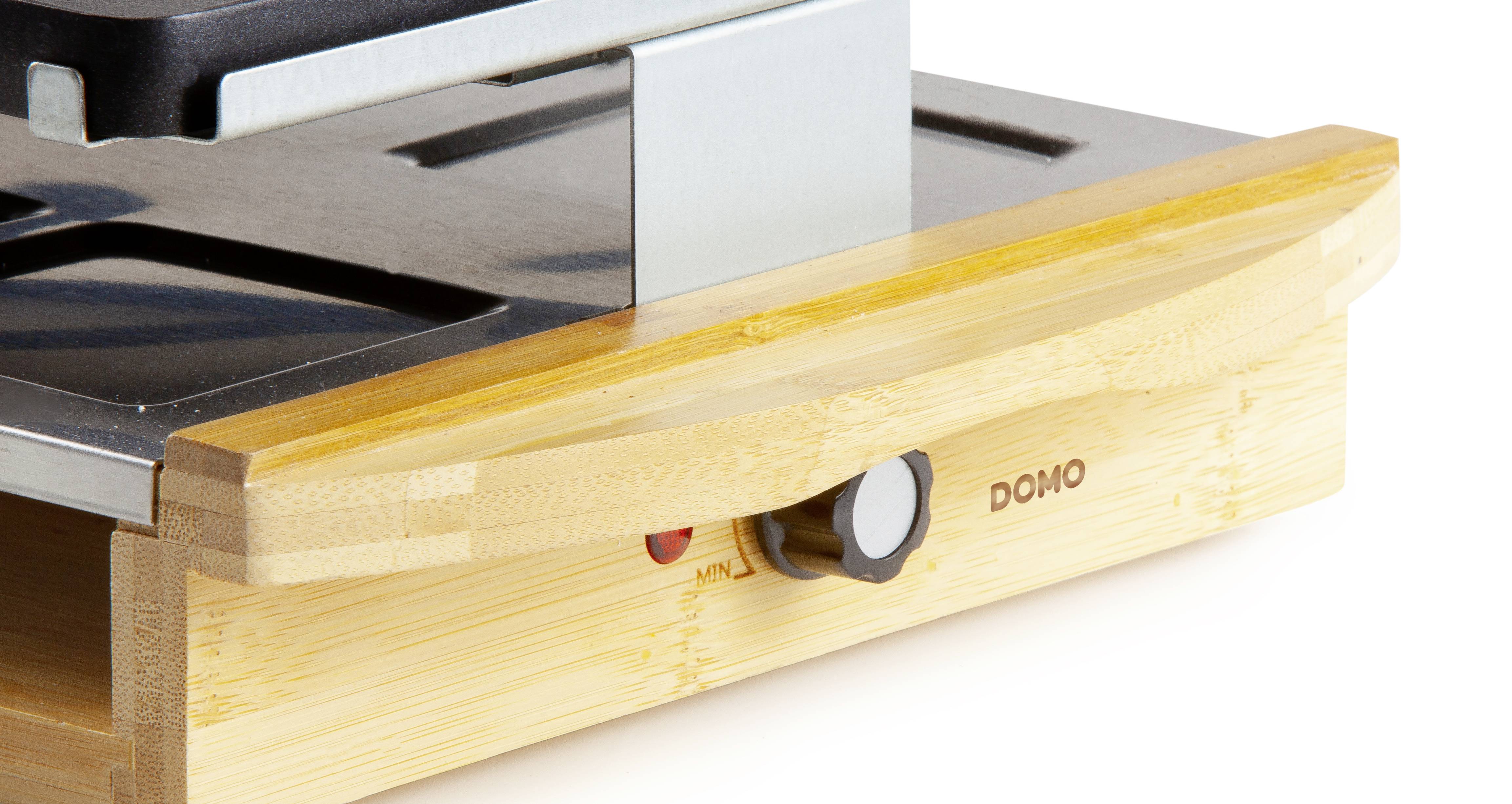 Ein Waffeleisen mit Holzbasis und einem Schalter an der Vorderseite. Das Gerät trägt die Aufschrift 'DOMO'.