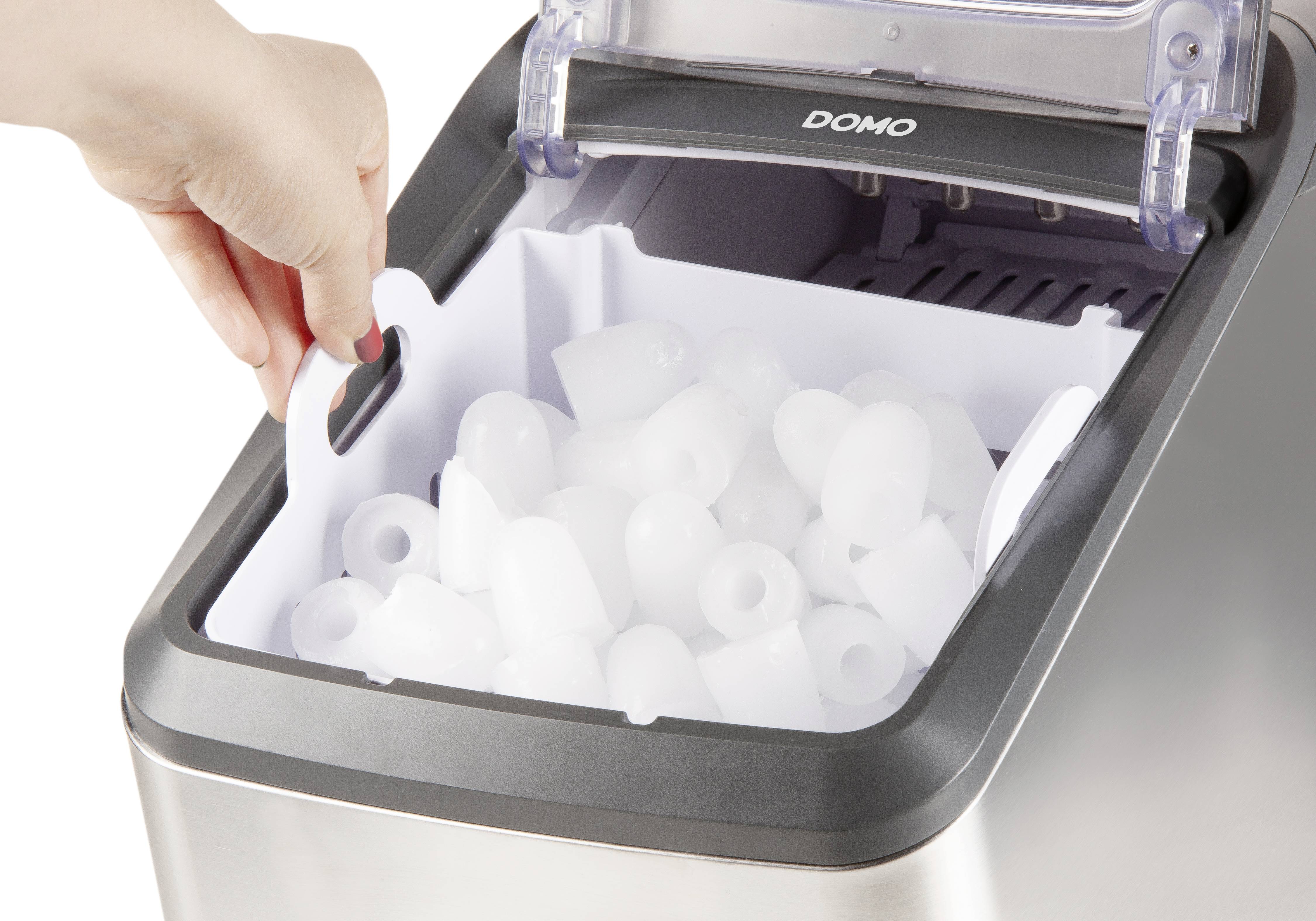 Eine Hand nimmt ein Fach voller Eiswürfel aus einer Eismaschine. Die Eismaschine ist silbern und die Vorderseite ist geöffnet.