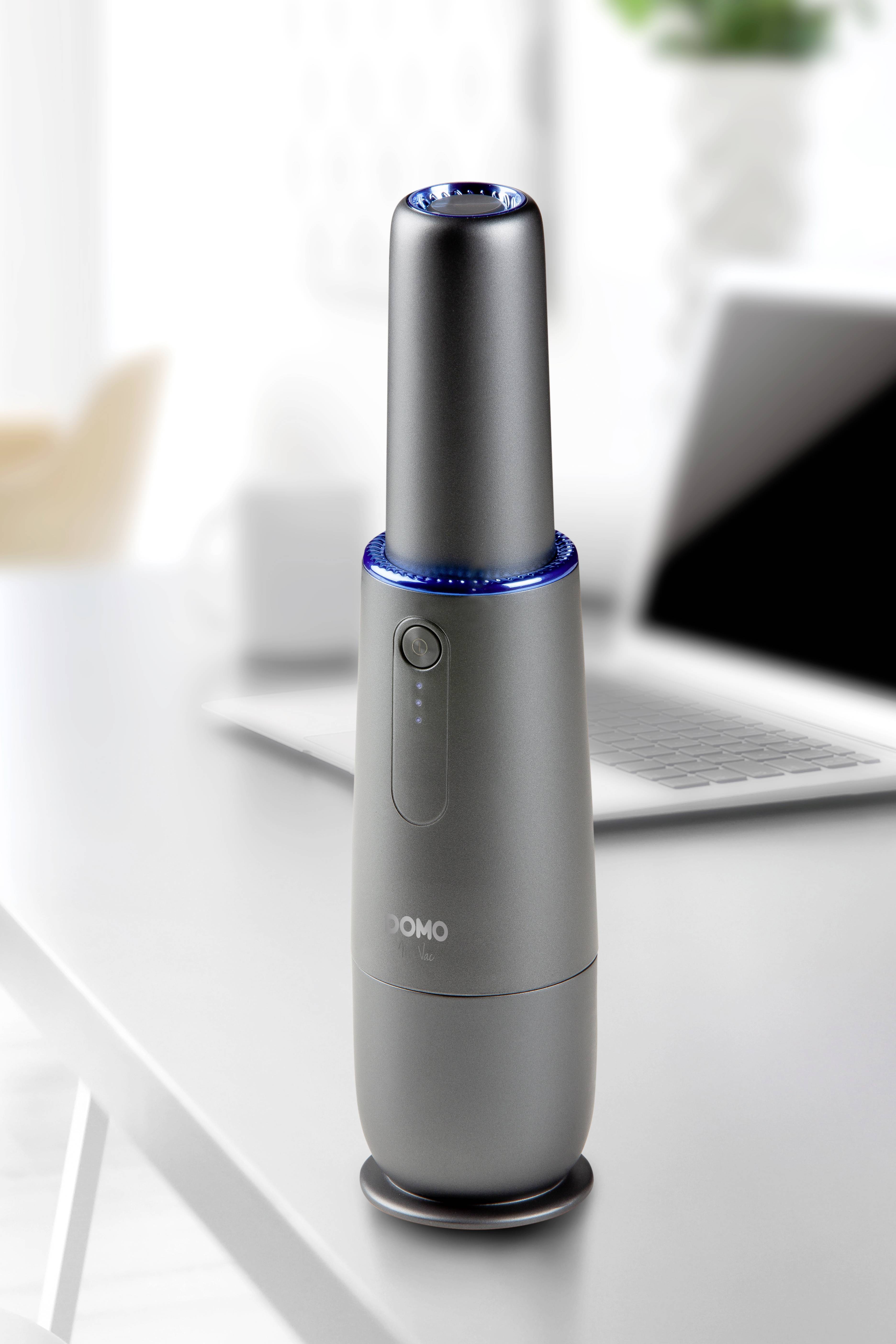 Ein schlanker, grauer Luftreiniger steht auf einem modernen Schreibtisch vor einem Laptop. Im Hintergrund sind unscharf Möbel erkennbar.