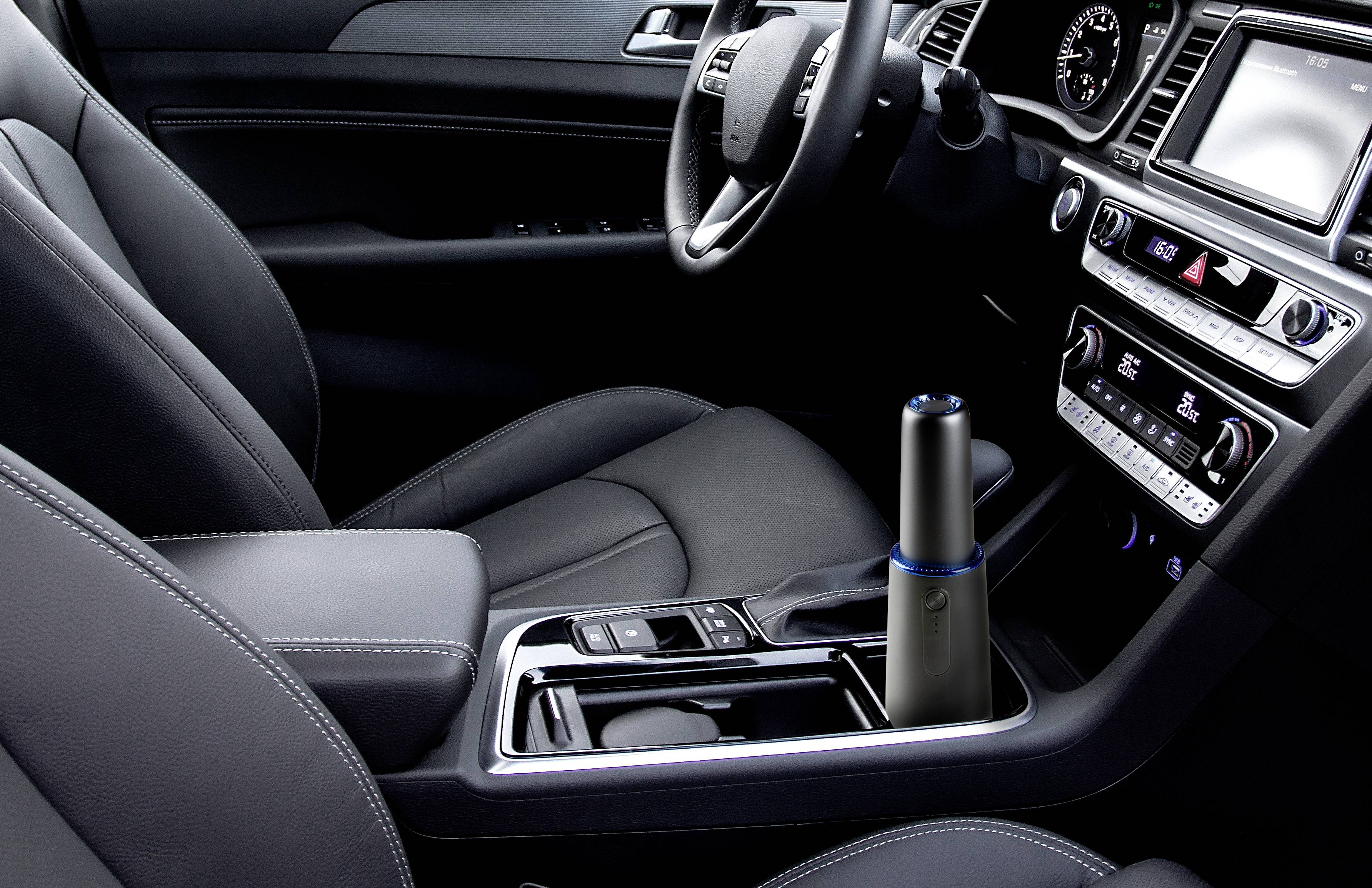 Innenraum eines Autos mit grauen Ledersitzen, Mittelkonsole mit Getränkehalter, elektronischen Tasten und einem modernen Display.