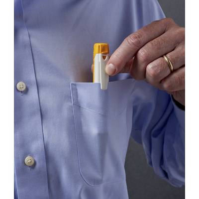 Eine Person steckt einen gelben Inhalator in die Brusttasche eines blauen Hemdes.
