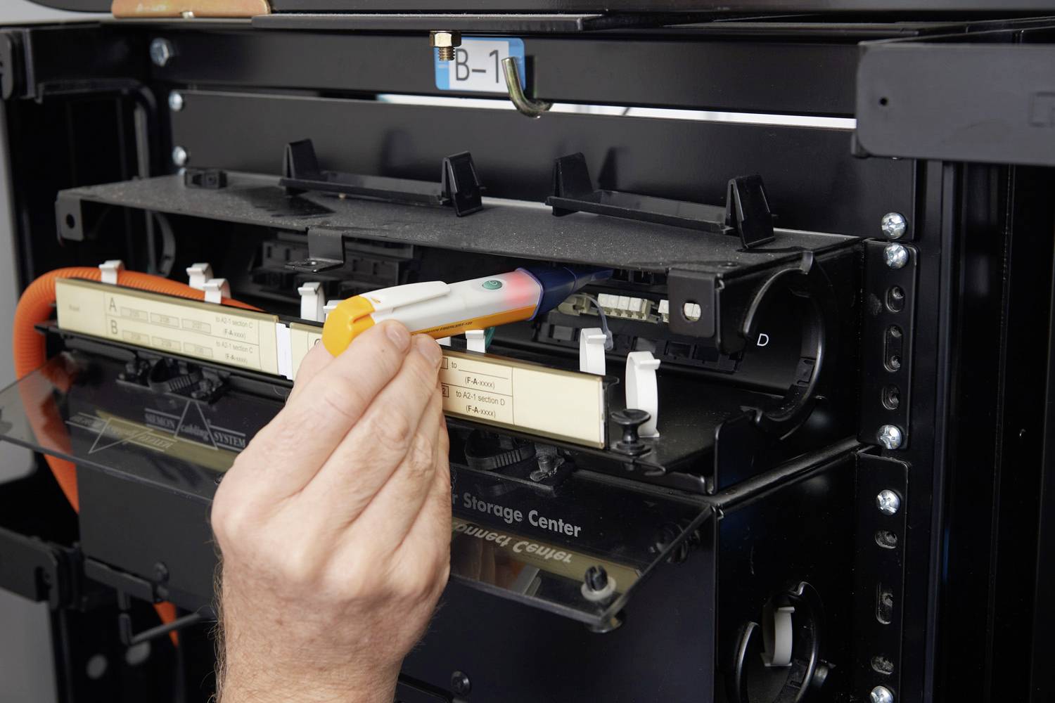 Eine Hand installiert eine Patrone in einen 3D-Drucker. Im Hintergrund sind Teile des Druckers sichtbar.