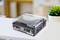 Ein Plattenspieler mit durchsichtiger Abdeckung sitzt auf einem Tisch. Im Hintergrund ist eine grüne Pflanze zu sehen.