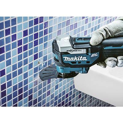 Eine Person mit Handschuhen verwendet ein blaues Oszillationswerkzeug, um Fliesen an einer mit blauen Mosaikfliesen abgedeckten Wand zu schneiden.