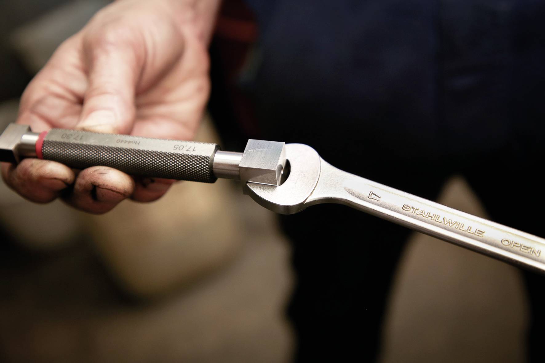 Eine Hand, die einen Drehmomentschlüssel mit einem quadratischen Socketadapter hält, was auf eine mechanische Reparaturaufgabe hindeutet.