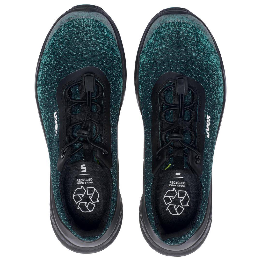 Ein Paar grüne Sportschuhe von oben, mit schwarzer Schnürung und recyceltem Material-Logo auf den Innensohlen.