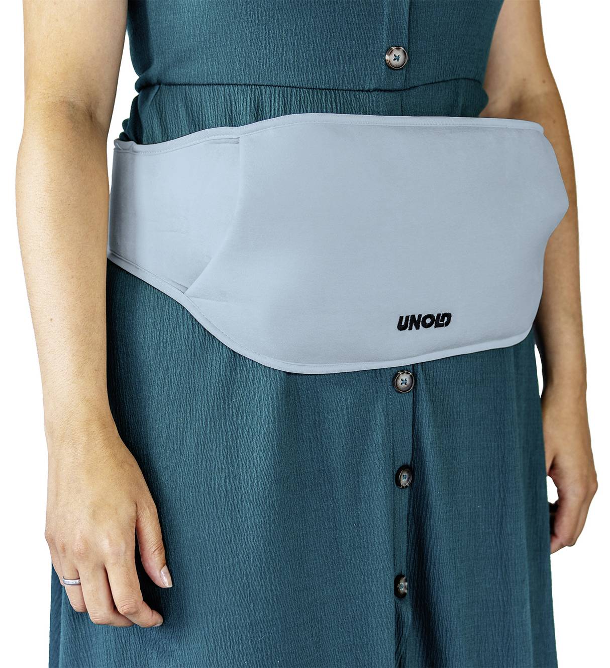 Eine Person trägt ein blaues Heizkissen um die Taille, über einem grünen Kleid. Das Kissen zeigt das Logo 'UNOLD'.