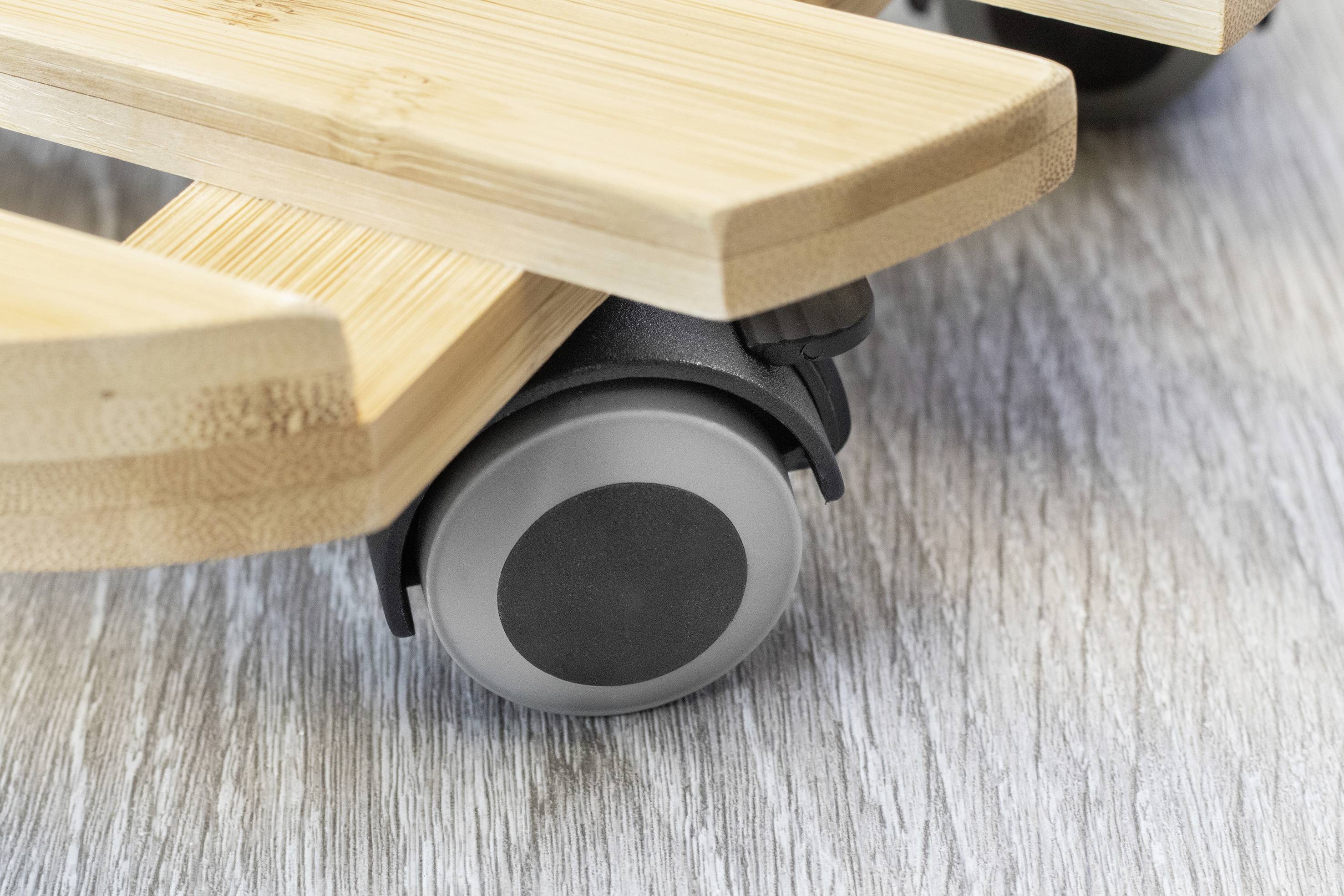 Nahaufnahme eines hölzernen Möbelstücks mit einer grauen Rolle auf einem hellen Holzboden.