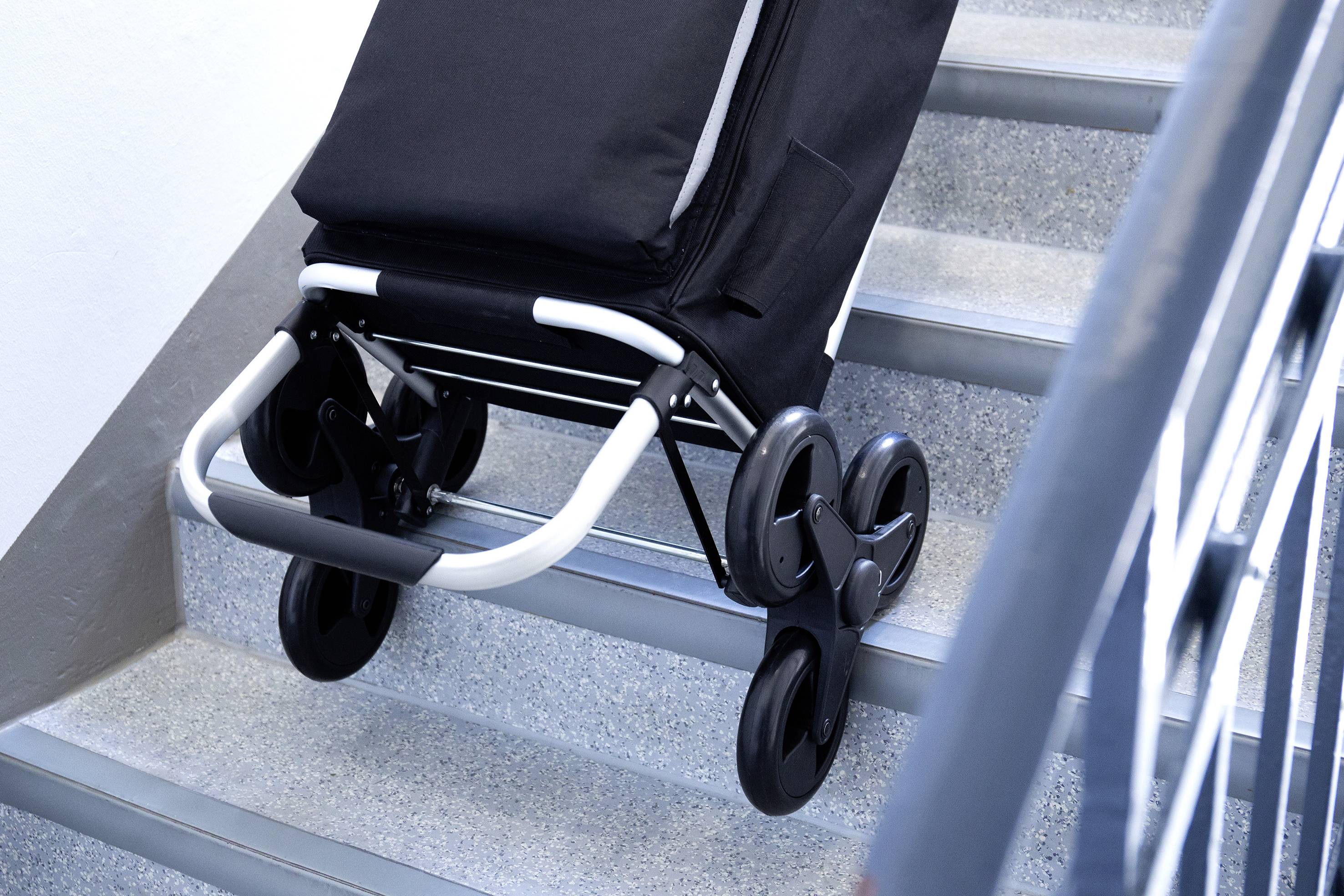 Kinderwagen mit schwarzen Stoffbezügen auf einer Treppe; zeigt Rolltechnik für Treppen hinunter.