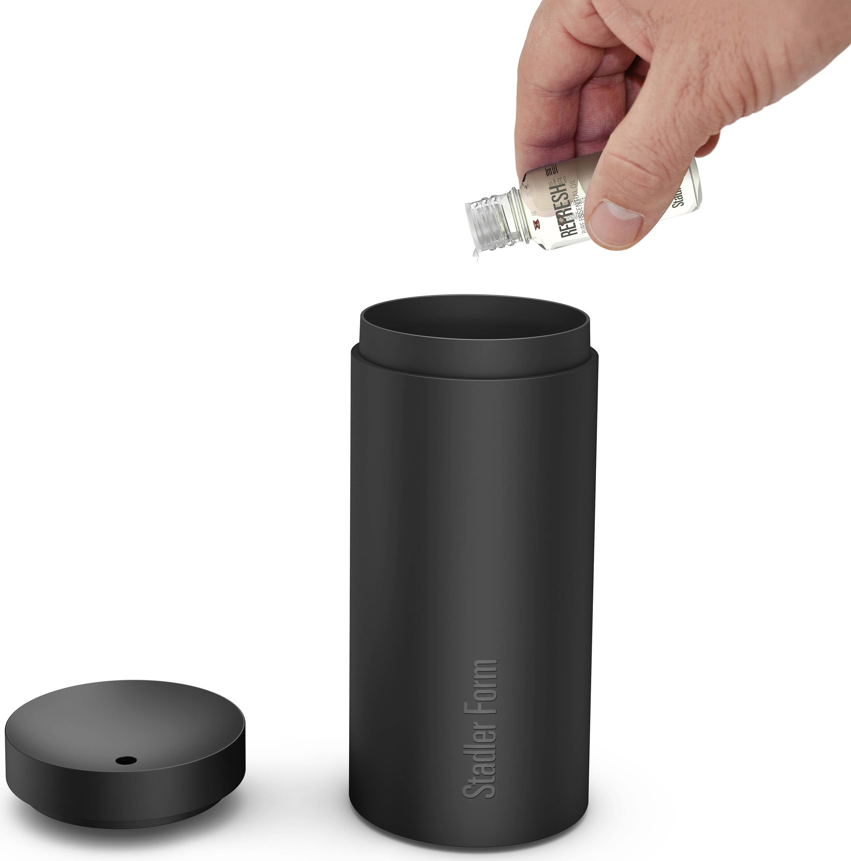 Eine Hand tropft ätherisches Öl in einen geöffneten schwarzen Aroma-Diffuser. Der Diffuser zeigt das Logo 'Stadler Form'.