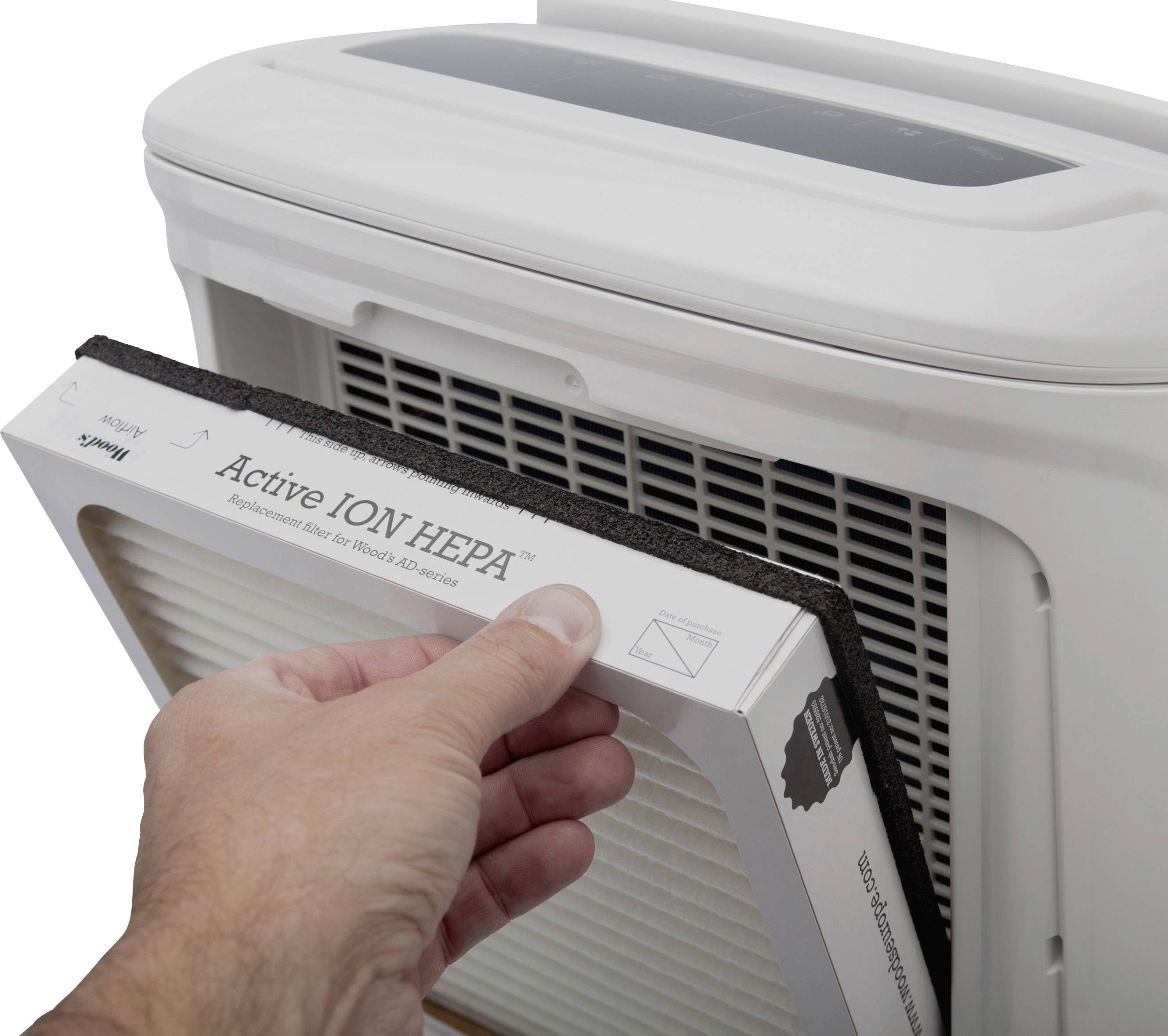 Eine Hand wechselt den HEPA-Filter eines weißen Luftreinigers. Der Filter ist rechteckig und wird auf der Vorderseite eingesetzt.