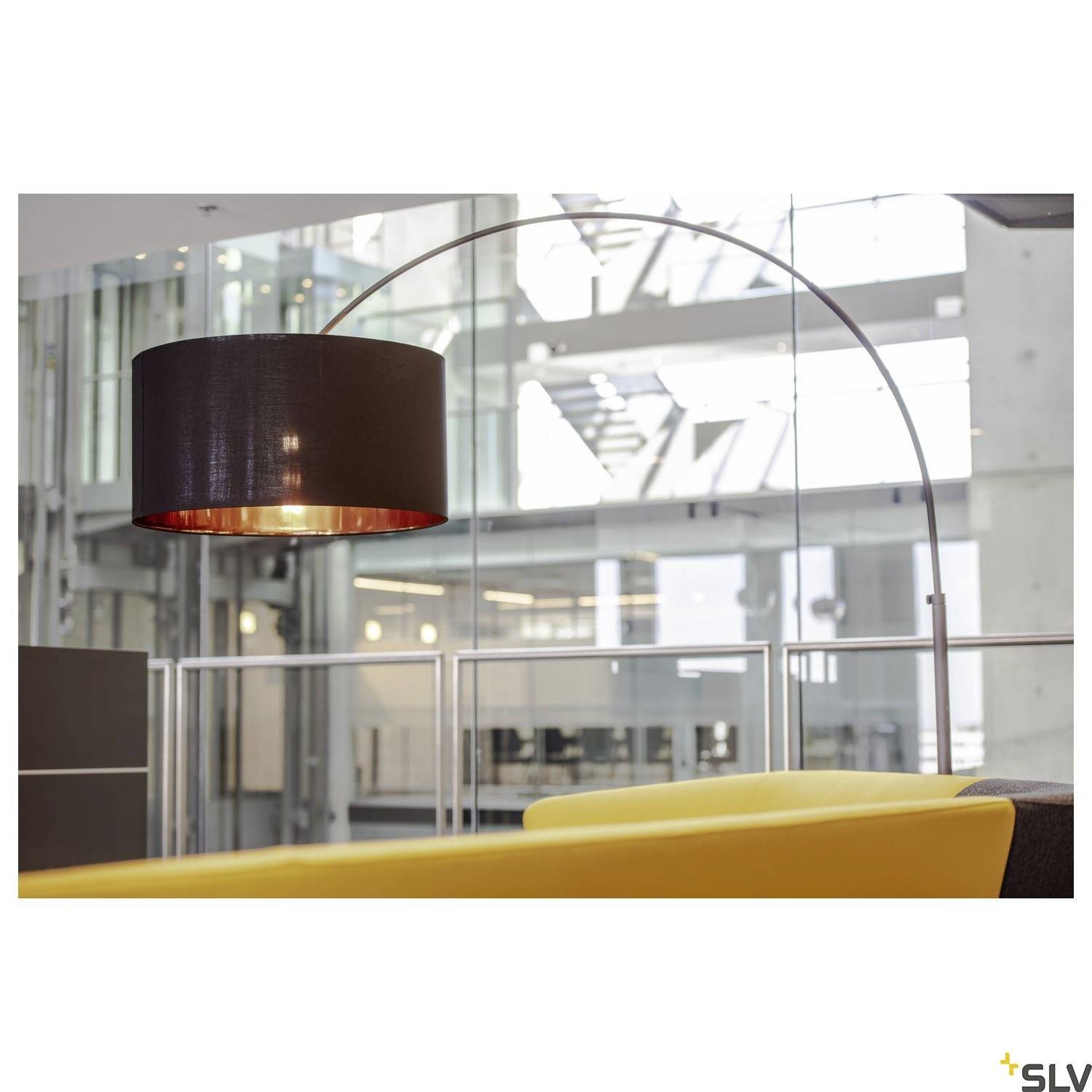 Eine moderne Lampe mit großem, runden Lampenschirm hängt in einem hellen, modernen Raum. Im Hintergrund sind Glaswände zu sehen.