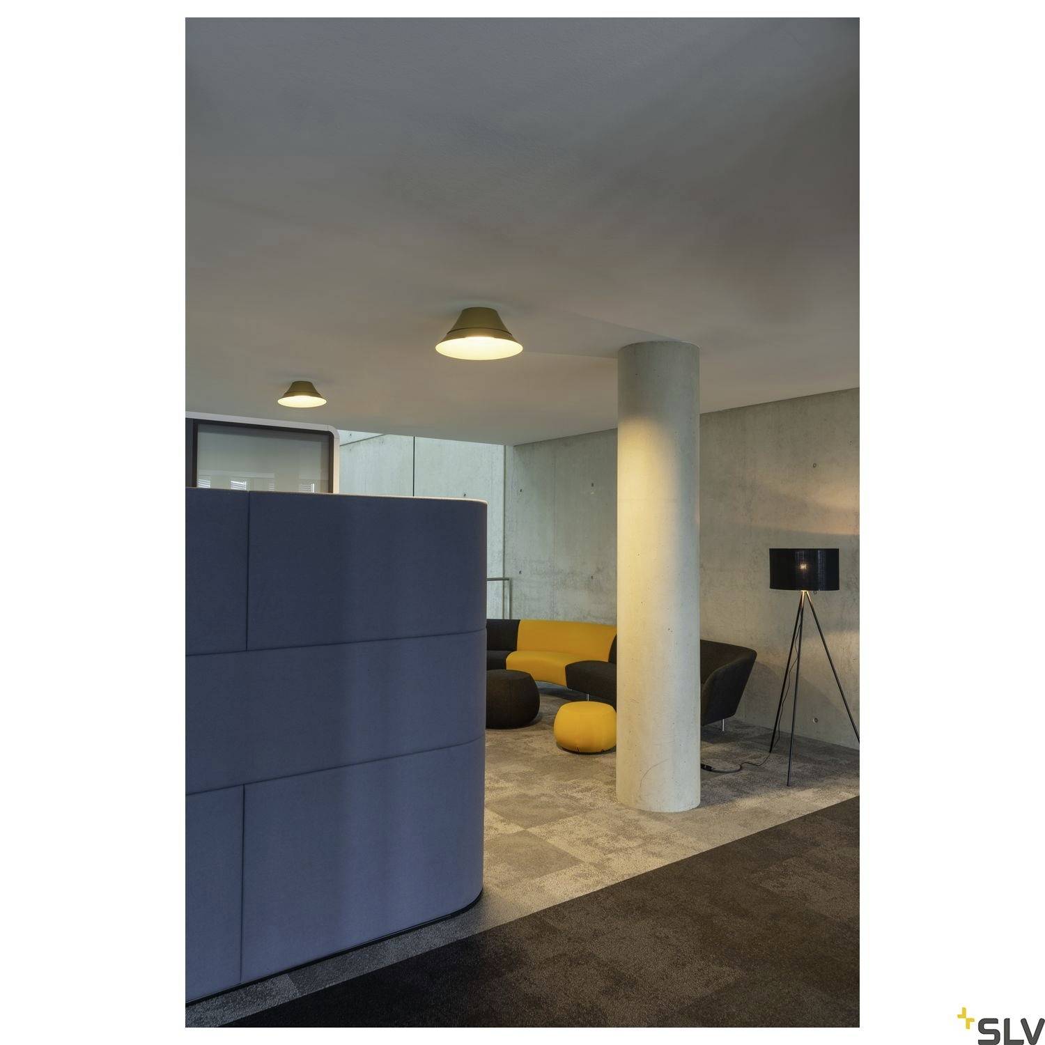 Moderne Bürolounge mit grauer Trennwand, gelbem Sofa, dunklen Hockern und minimalistischer Stehleuchte vor Betonwand.