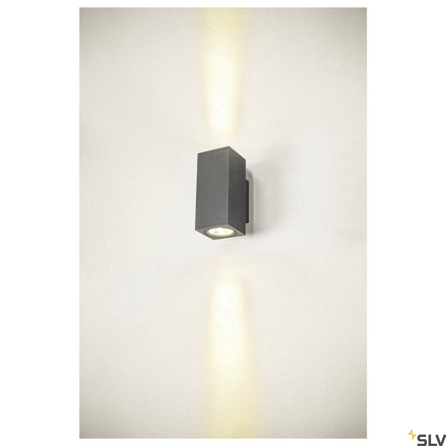 Wandleuchte in rechteckiger Form, leuchtet nach oben und unten an einer weißen Wand, erzeugt getrennte Lichtkegel für stilvolle Beleuchtung.