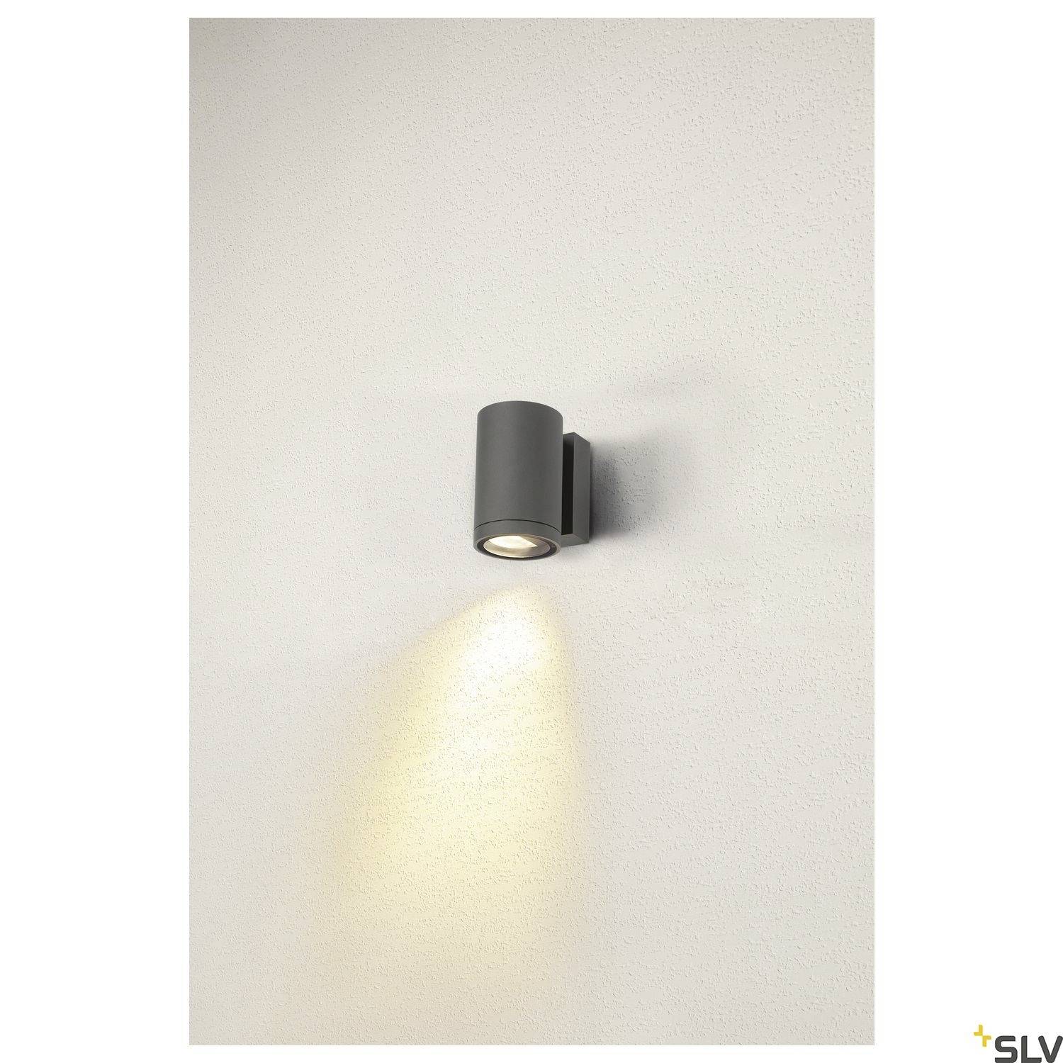 Schwarz-graue Wandleuchte, die sanftes Licht nach unten auf eine cremefarbene Wand wirft. Minimalistisches, modernes Design.