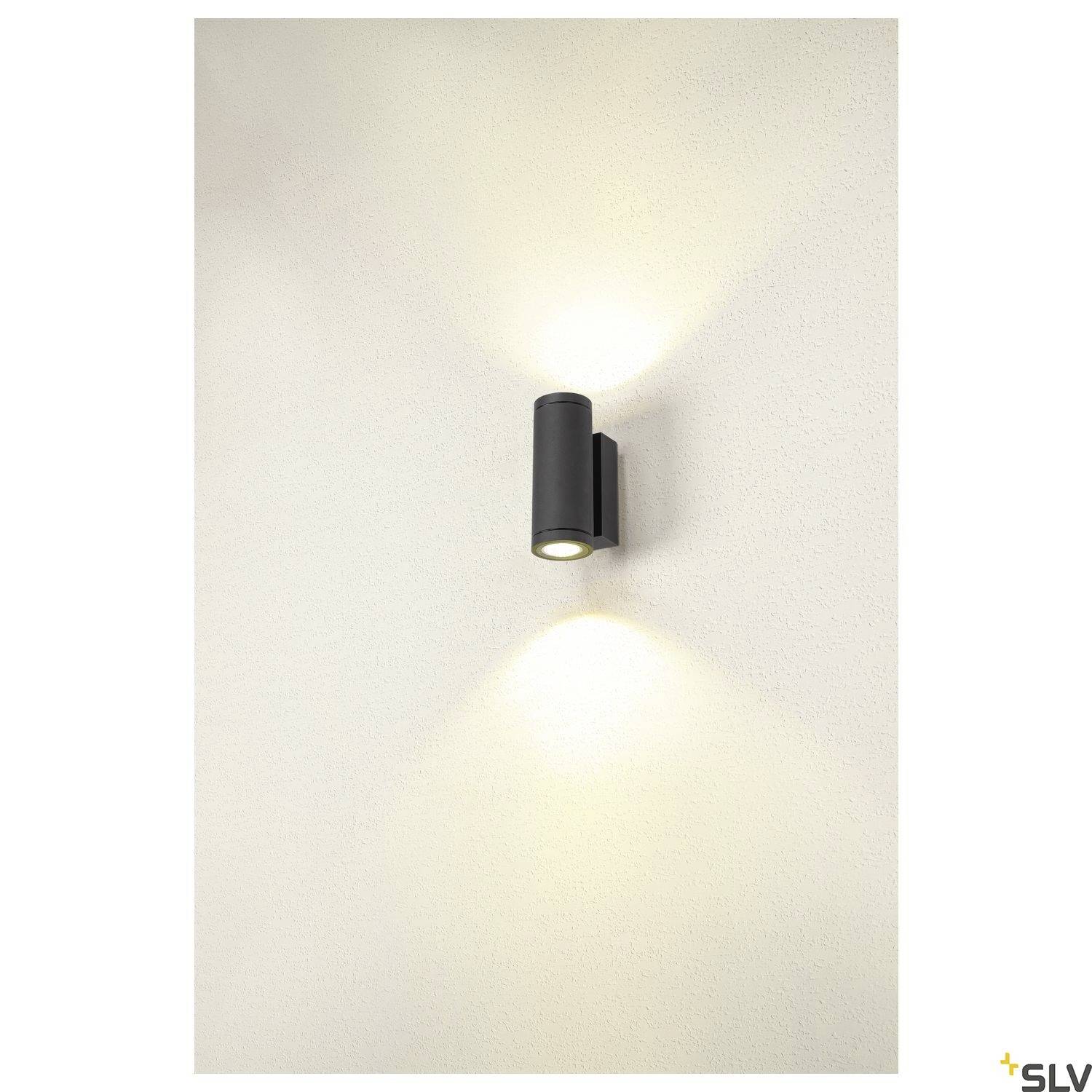 Eine moderne, schwarze Wandlampe strahlt Licht nach oben und unten gegen eine weiße Wand.