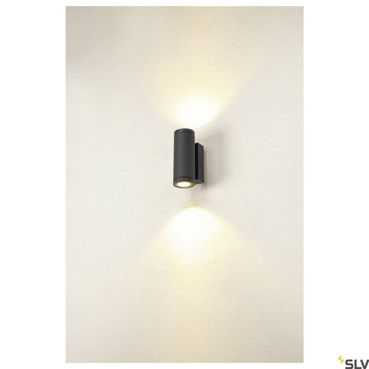 Wandleuchte aus schwarzem Metall mit nach oben und unten gerichtetem warmem Lichtstrahl auf einer weißen Wand.