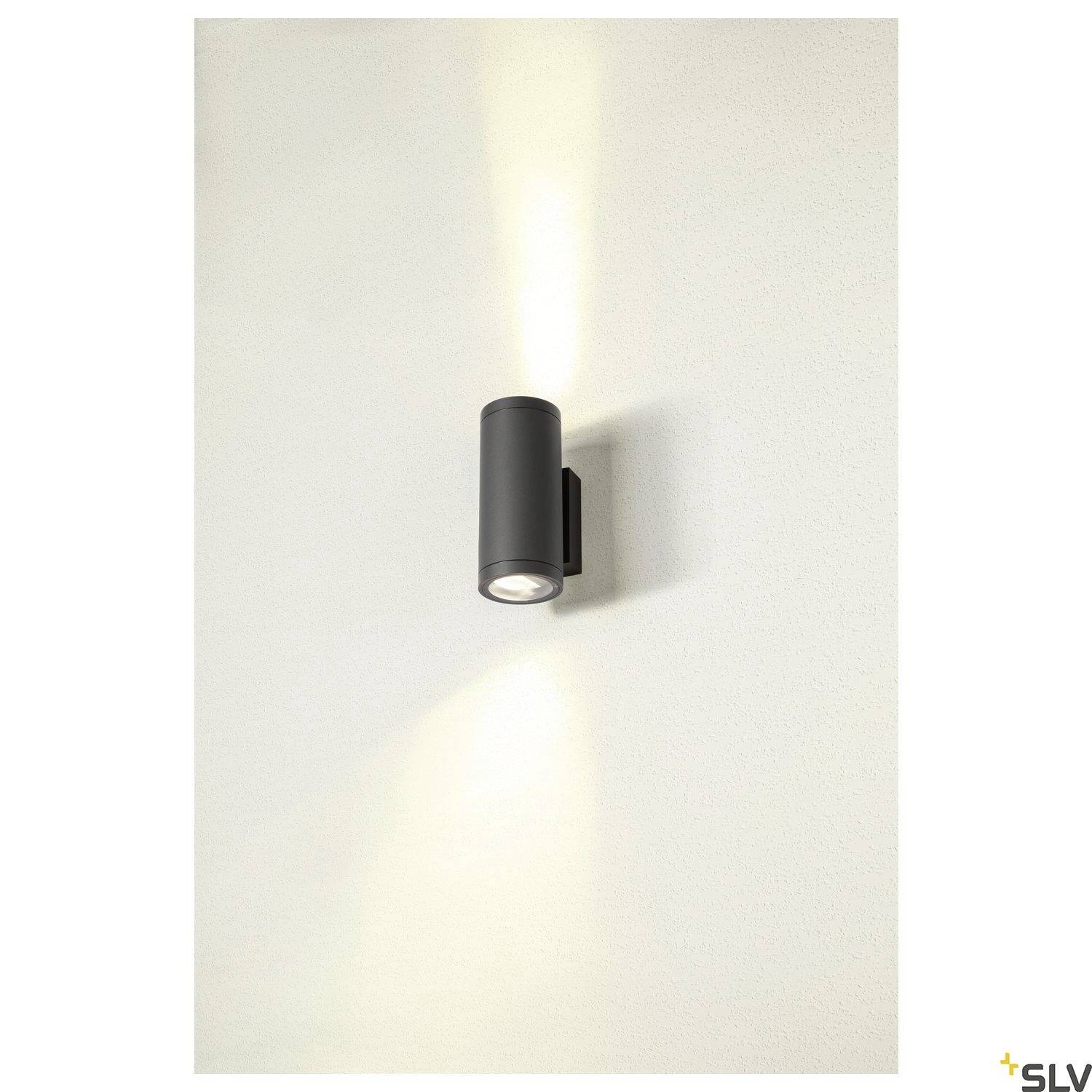 Wandleuchte in zylindrischer Form, strahlt nach oben und unten Licht ab. Moderne, minimalistische Ästhetik auf weißer Wand.