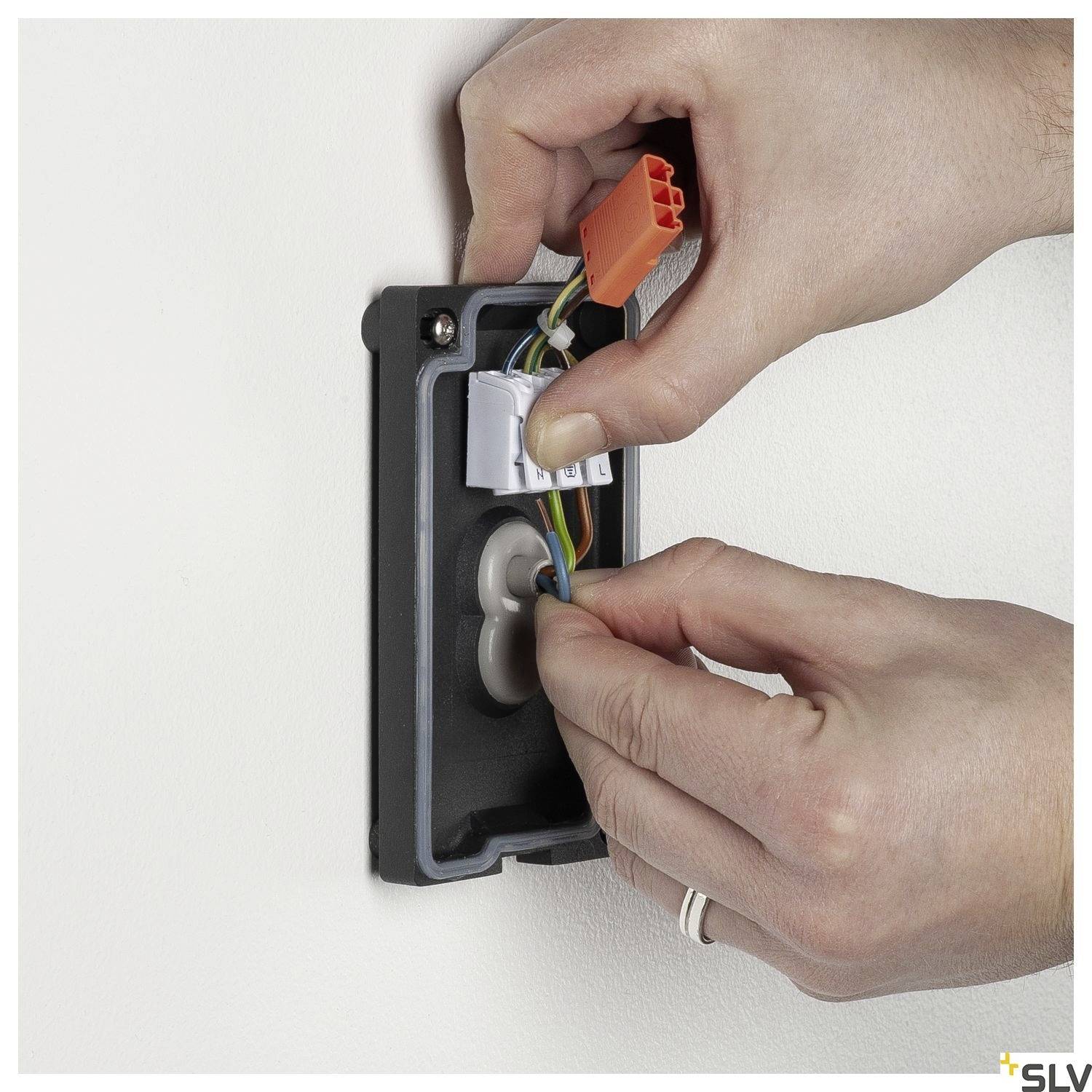 Eine Person installiert eine elektrische Anschlussdose in einer Wand und verbindet Kabel mittels Wago-Klemmen.