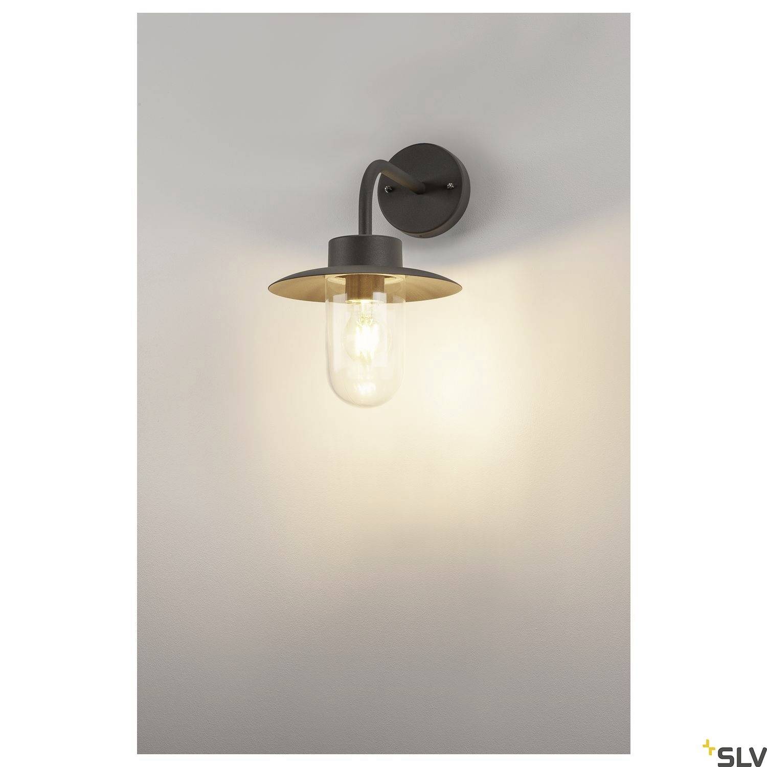 Wandlampe mit dunklem Metallhalterung und sichtbarer Glühbirne, die warmes Licht abgibt, an einer hellen Wand montiert.
