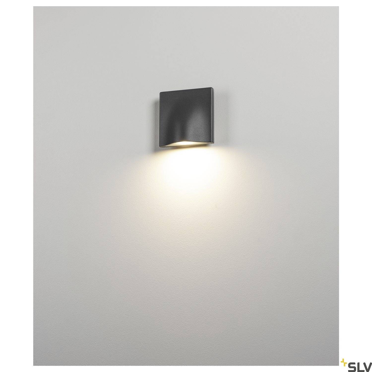 Wandleuchte an einer weißen Wand, die nach unten gerichtetes warmes Licht ausstrahlt.