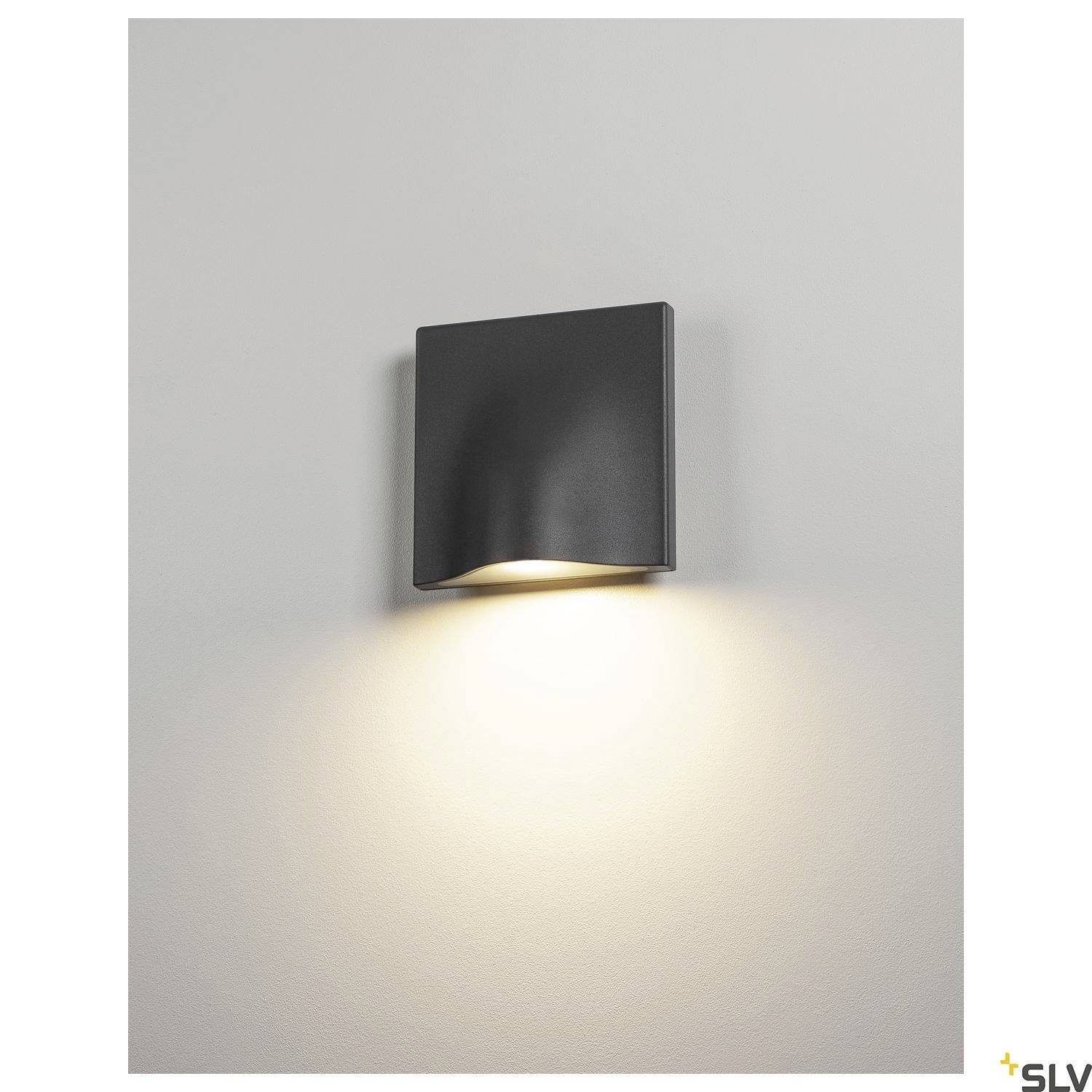 Eine moderne Wandlampe mit rechteckigem Gehäuse strahlt warmes Licht nach unten ab, geeignet für stilvolle Innenbeleuchtung.