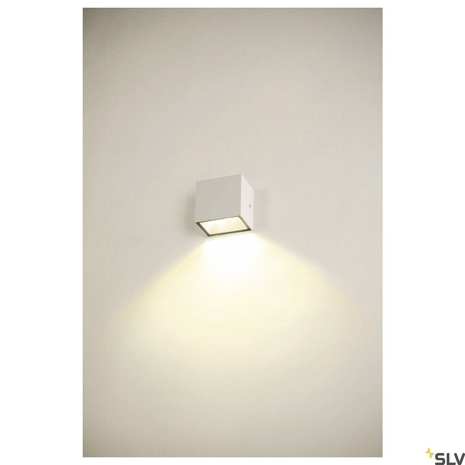 Wandleuchte in Würfelform mit nach unten abstrahlendem Licht auf weißer Wand.