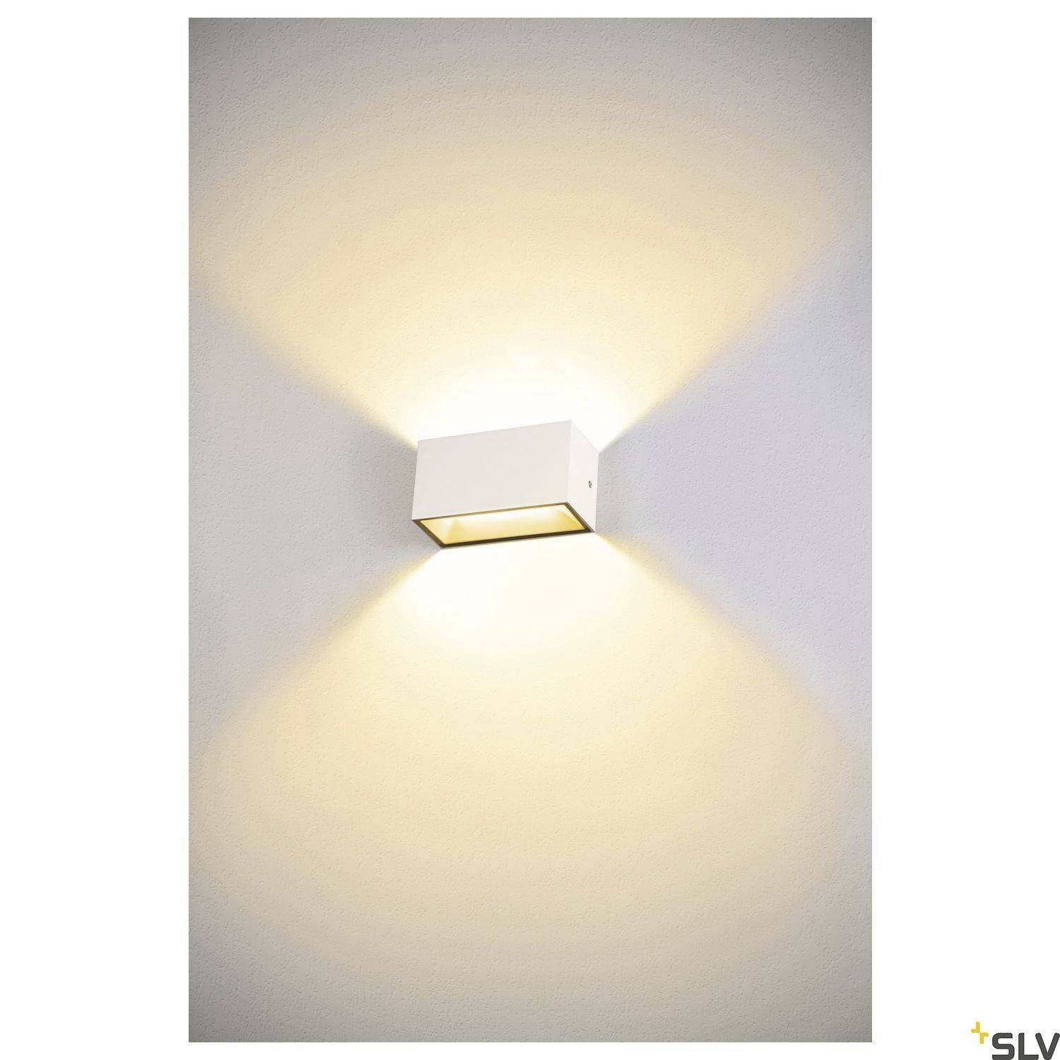 Weiße, quadratische Wandleuchte strahlt warmes Licht nach oben und unten auf graue Wand, erzeugt weiche Lichtkegel.