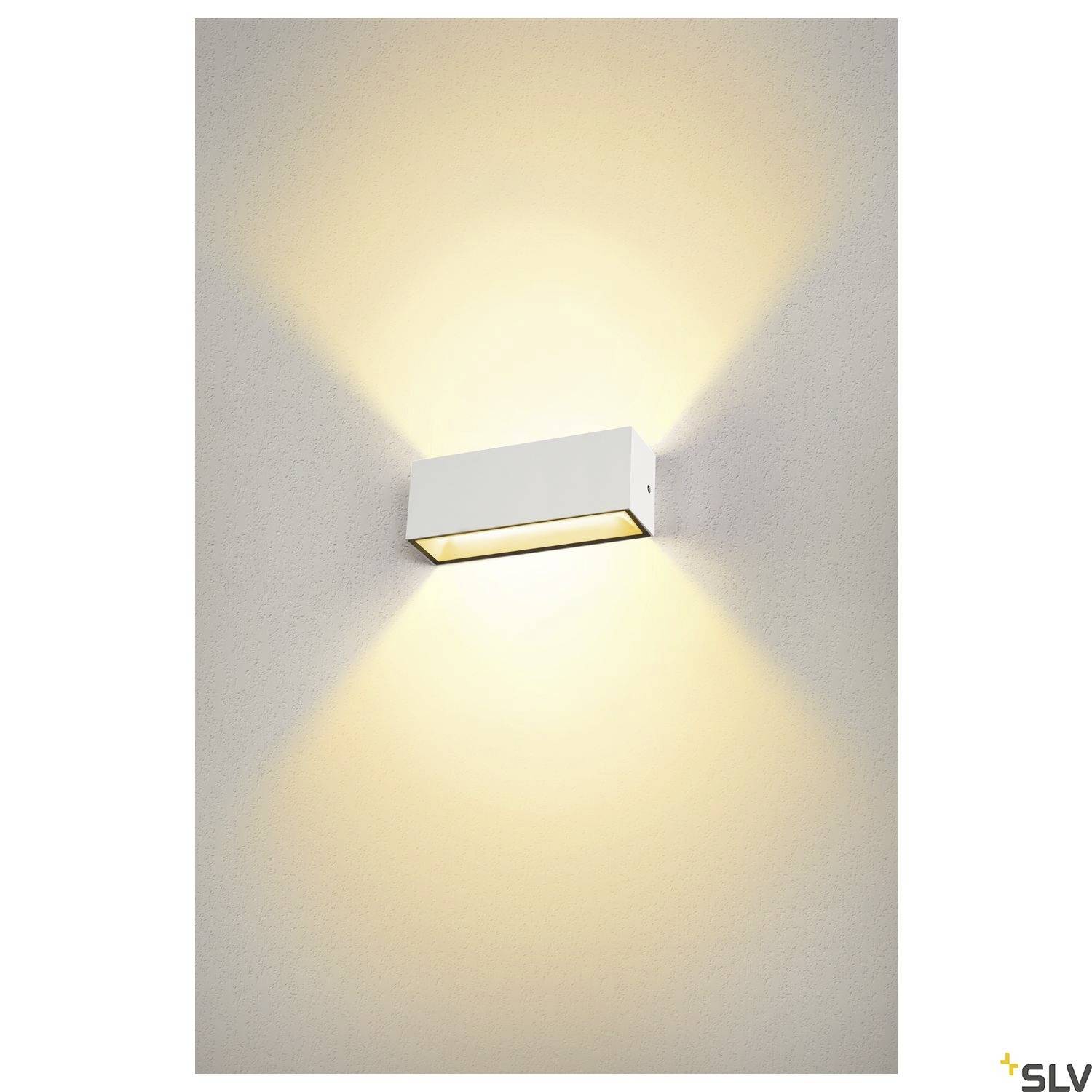 Rechteckige Wandlampe leuchtet warmes Licht nach oben und unten ab, montiert an einer hellen Wand. Minimalistisches Design.