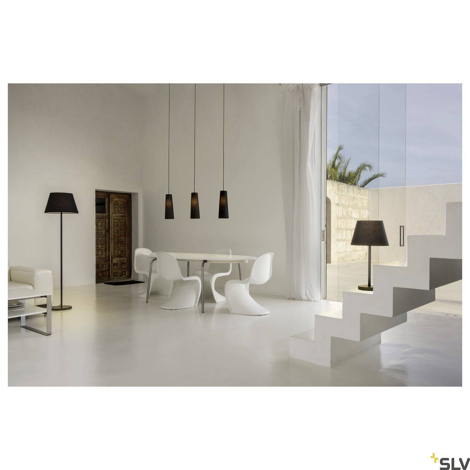 Modernes Wohnzimmer mit weißen Möbeln, großem Esstisch und stilvollen Lampen. Große Fenster bieten Blick auf den Außenbereich.