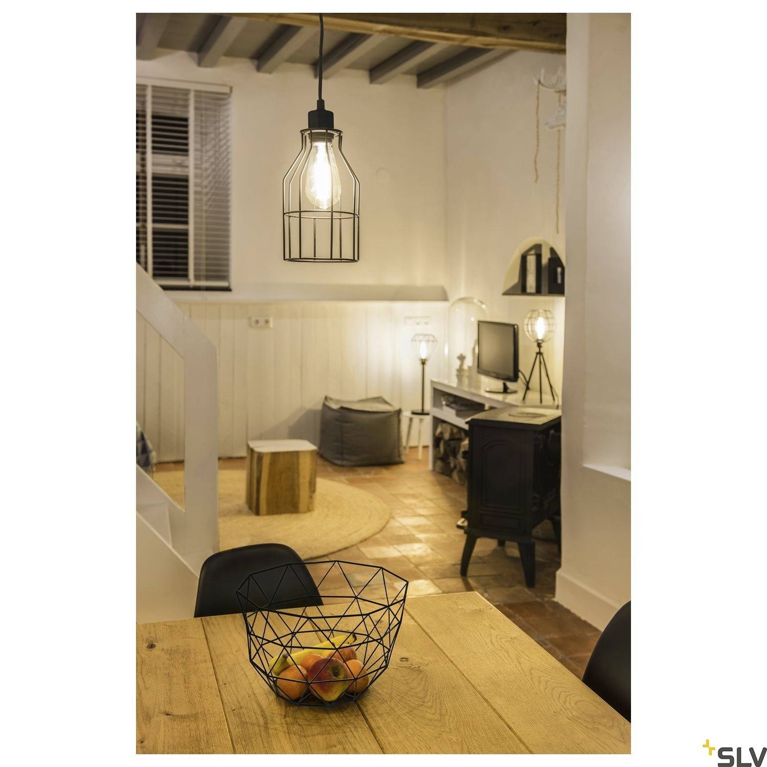 Ein gemütliches Wohnzimmer mit einem Tisch im Vordergrund, auf dem ein Obstkorb steht. Im Hintergrund sind ein Schreibtisch und Lampen.