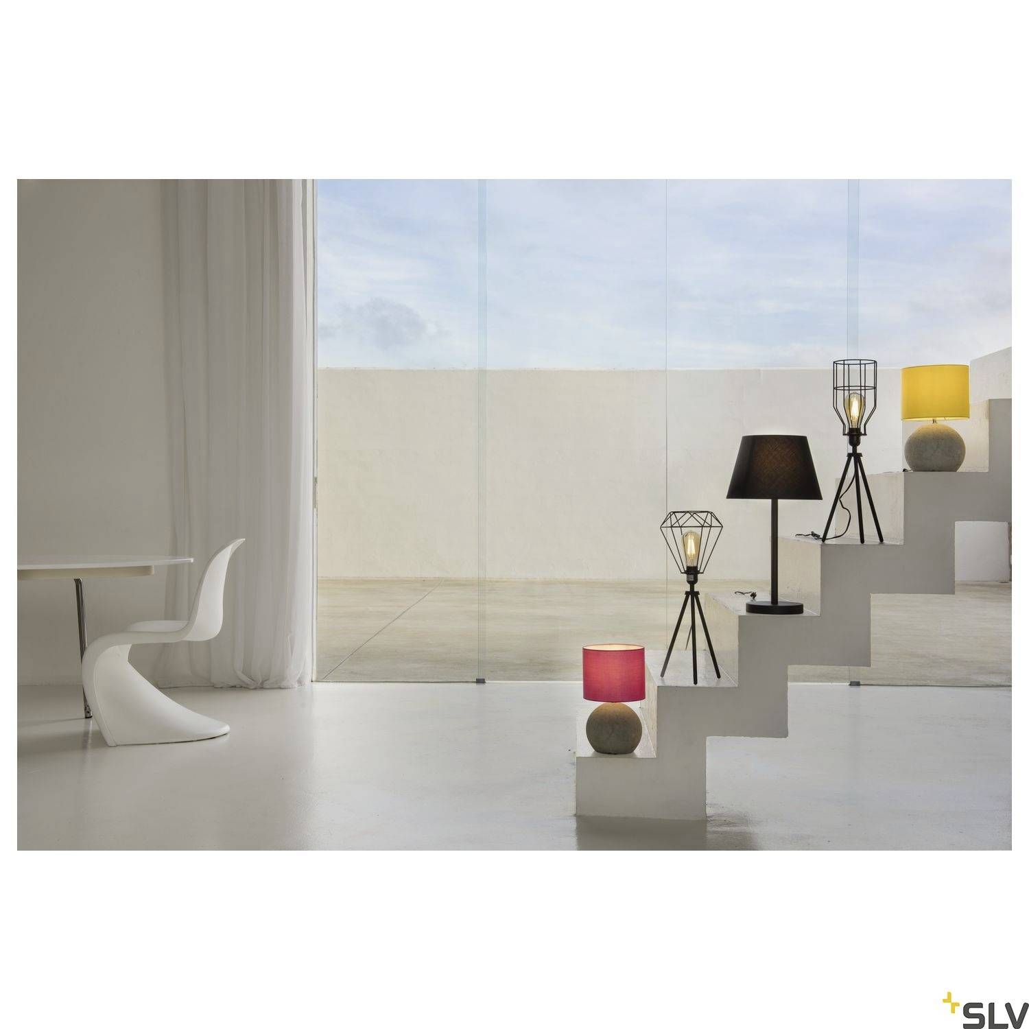 Eine moderne Einrichtung mit weißen Möbeln und Treppenregal mit mehreren minimalistischen Tischlampen vor einer Glaswand.