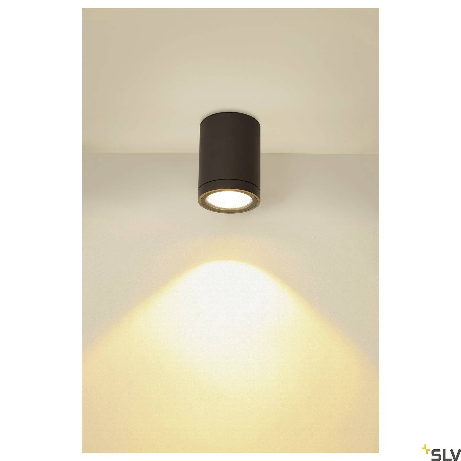 Deckenleuchte mit zylindrischem, schwarzem Gehäuse strahlt warmes Licht auf die Wand. Ideal für eine gemütliche Beleuchtung.