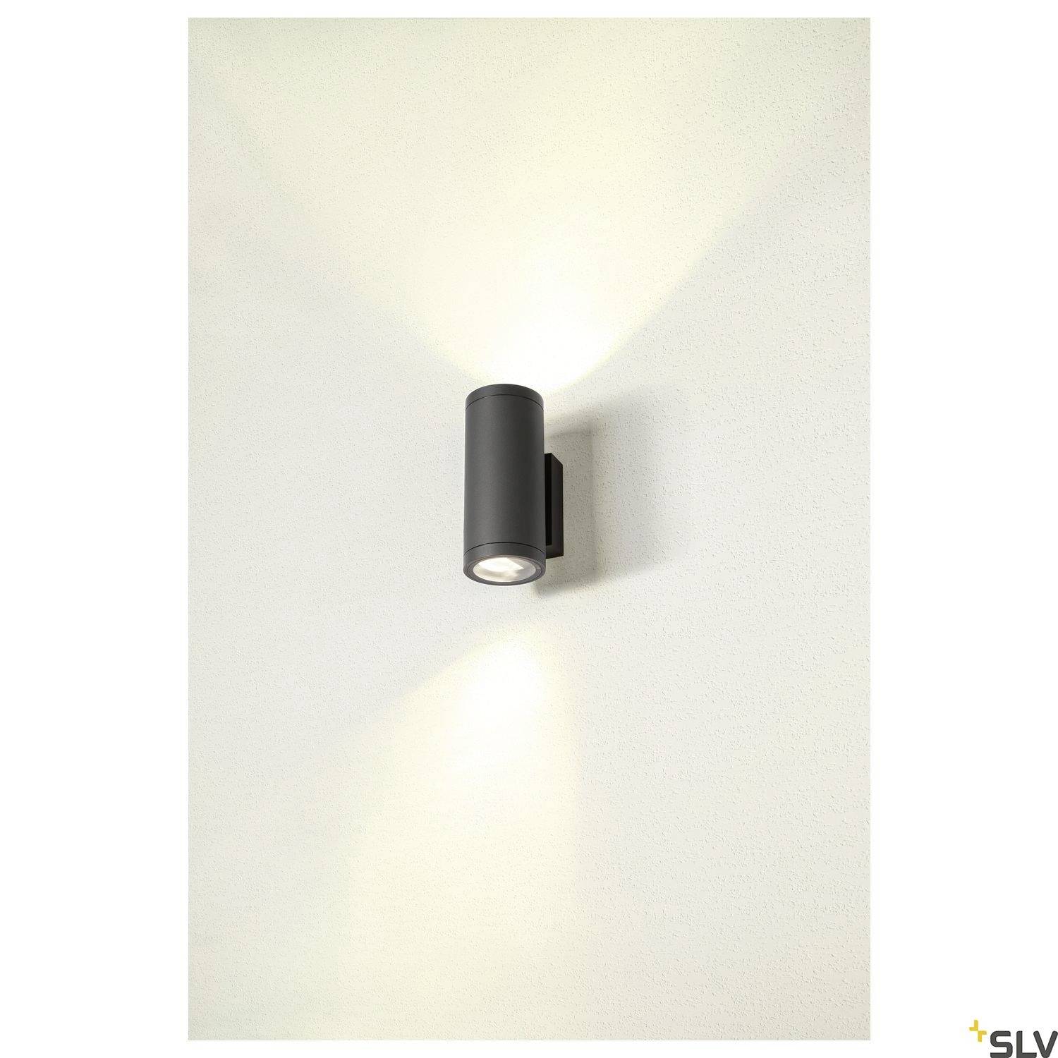 Wandleuchte mit zylindrischem Gehäuse strahlt Licht nach oben und unten aus. Wand erzeugt symmetrische Lichtkegel.