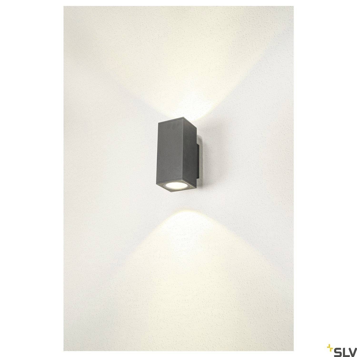 Außenlampe aus schwarzem Metall an einer Wand, strahlt Licht nach oben und unten und erzeugt ein sanftes Leuchten.