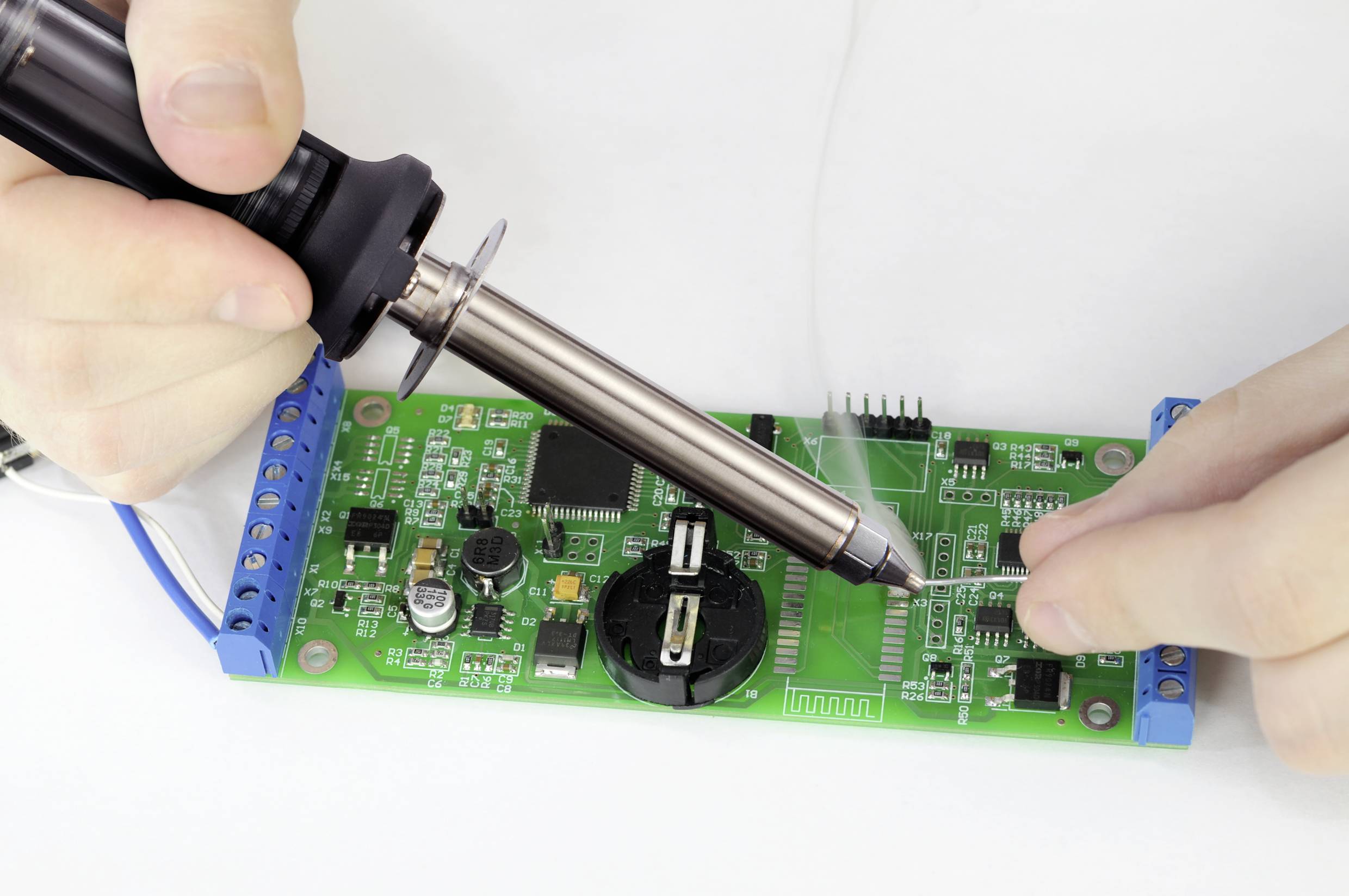 'Jemand lötet eine grüne Schaltkreisplatine.'