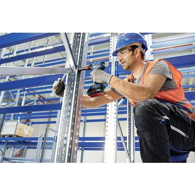 Eine Person auf einer Baustelle befestigt Metallträger mit einem Akkuschrauber. Sie trägt Sicherheitsausrüstung, einschließlich Helm und Weste.