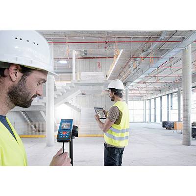 Bauarbeiter in Schutzkleidung nutzen digitale Geräte zur Vermessung in einem unfertigen Gebäude. Moderne Bauplanung und Technologie im Einsatz.